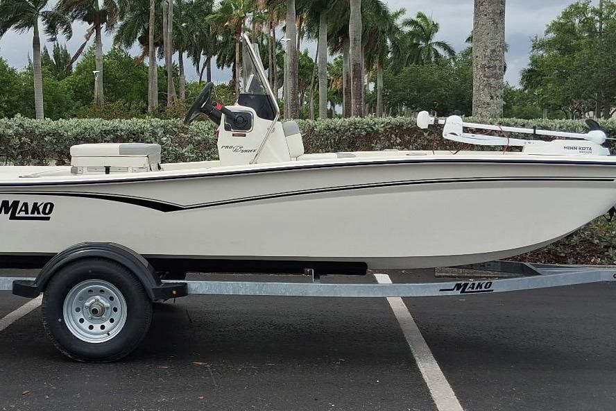 2026 Mako Pro Skiff 15 CC boat on trailer, parked outdoors with lush greenery background.