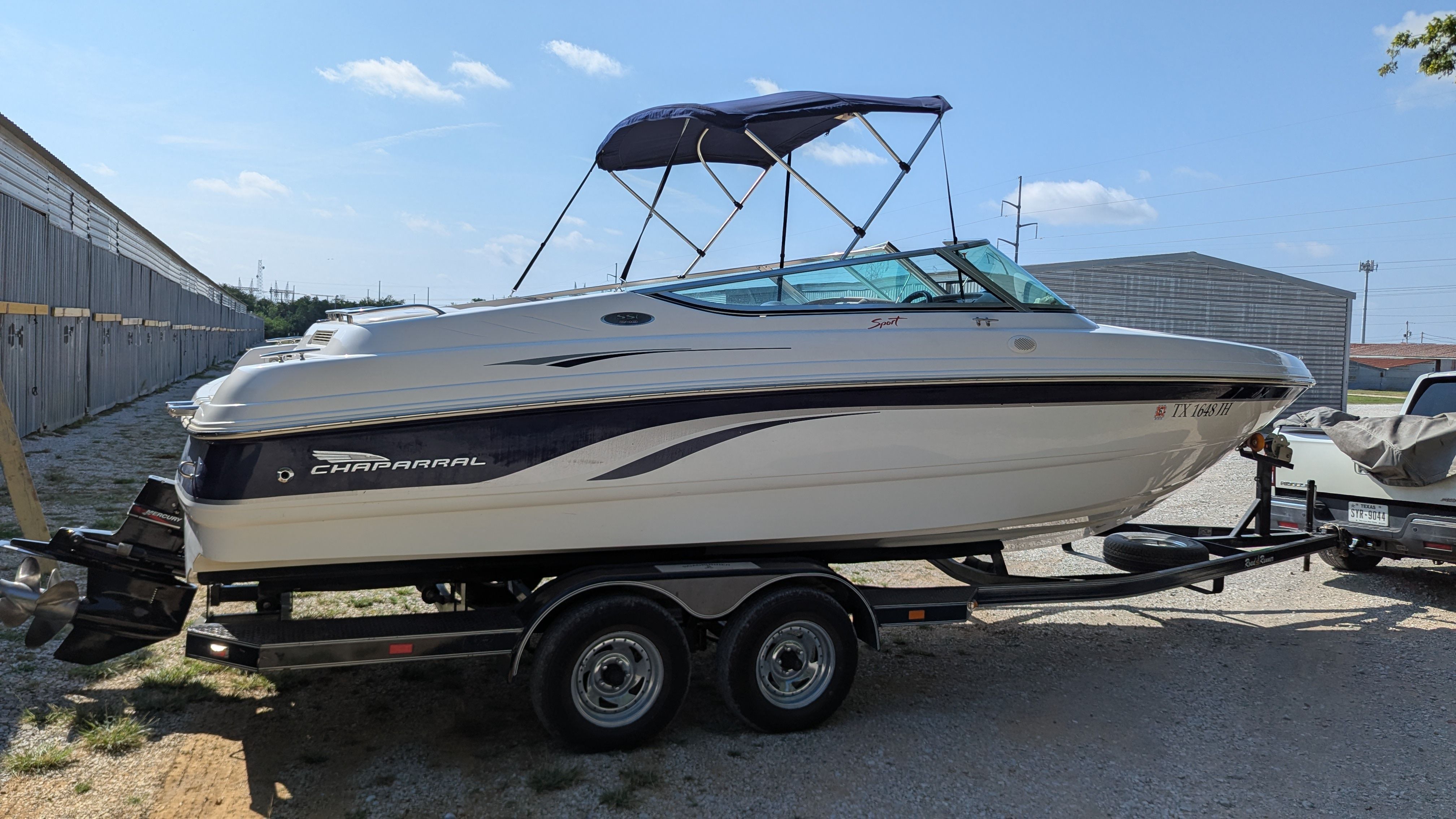 A 2000 Chaparral 240 SSi boat on a trailer, featuring a blue bimini top.