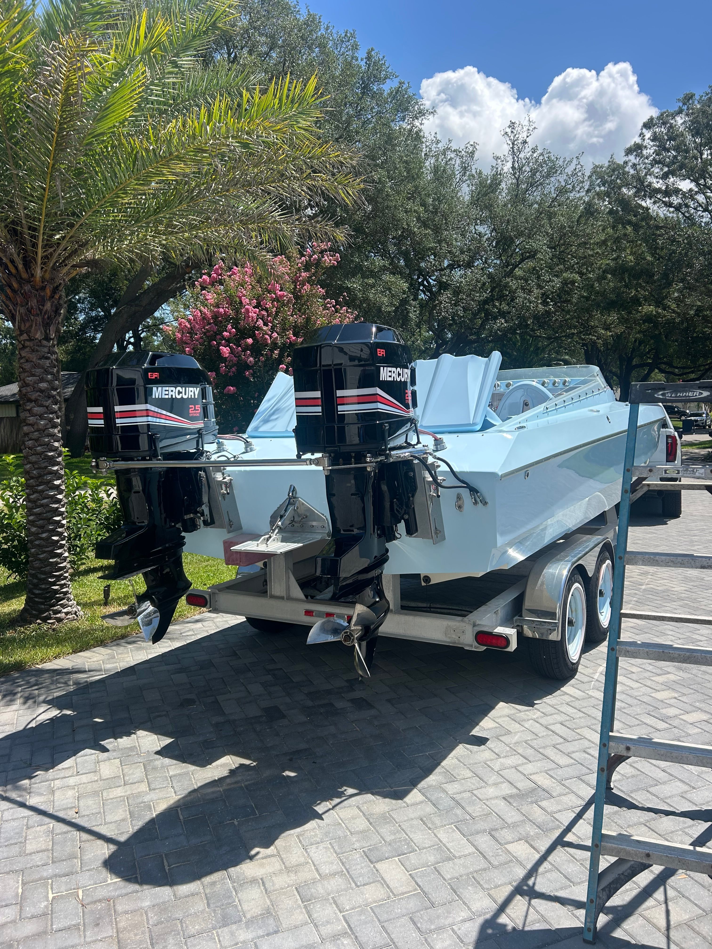 A 1992 Motion Marine 25 CAT on a trailer with two Mercury outboard engines.