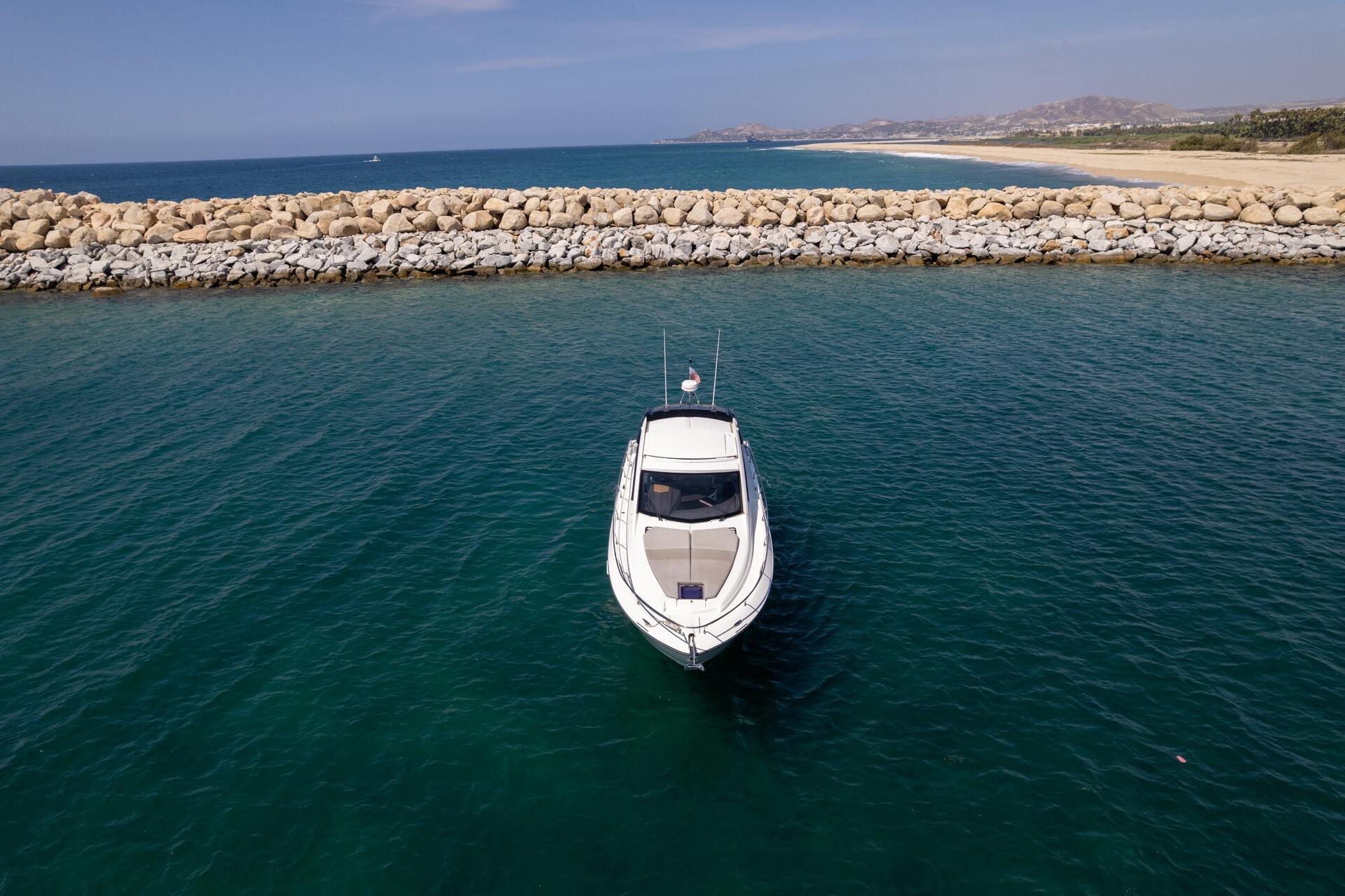 2019 Beneteau Gran Turismo 46 yacht on calm sea near rocky breakwater.