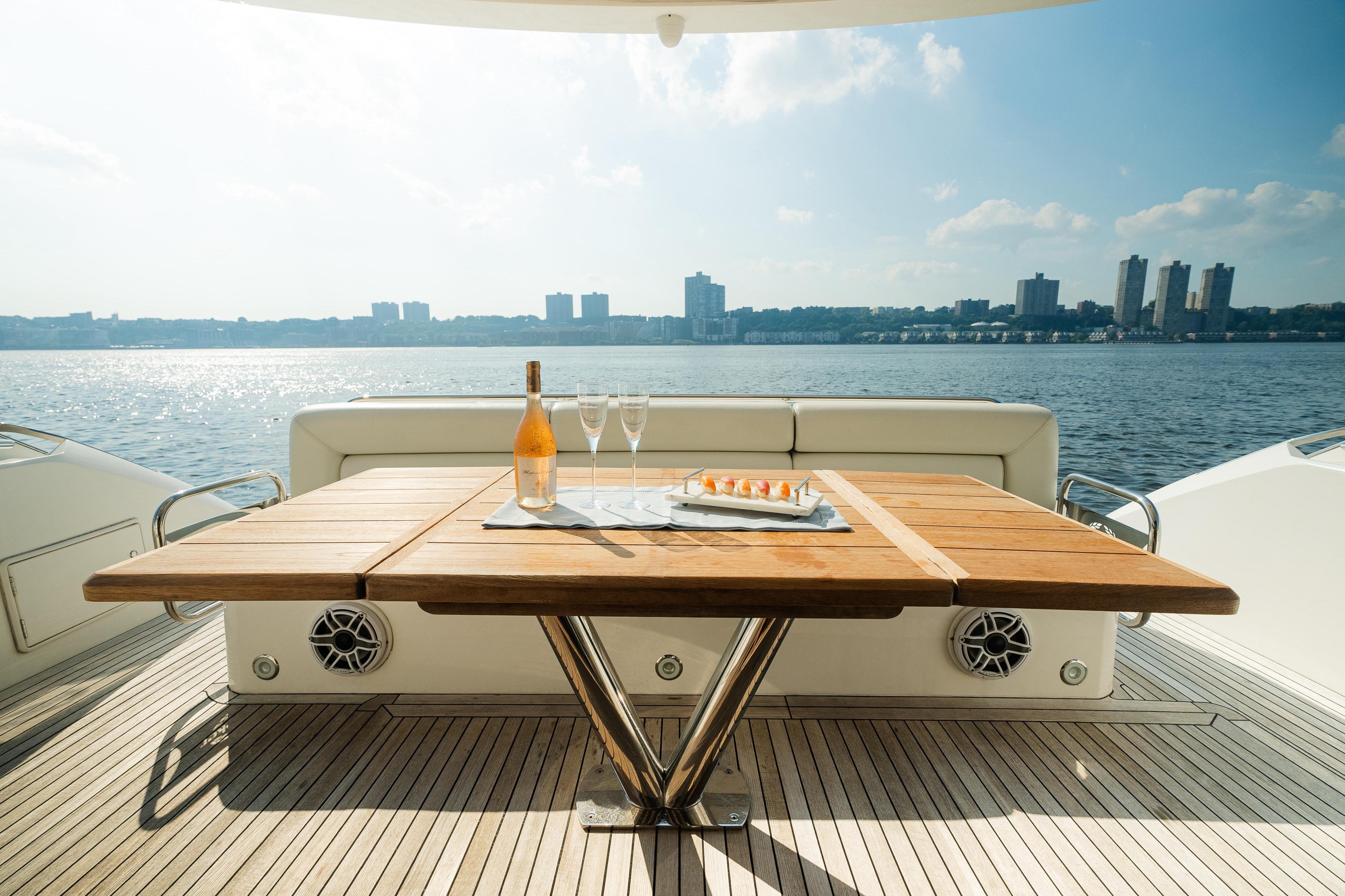 Luxury Sunseeker Manhattan 65 yacht deck with table, champagne, and waterfront view.