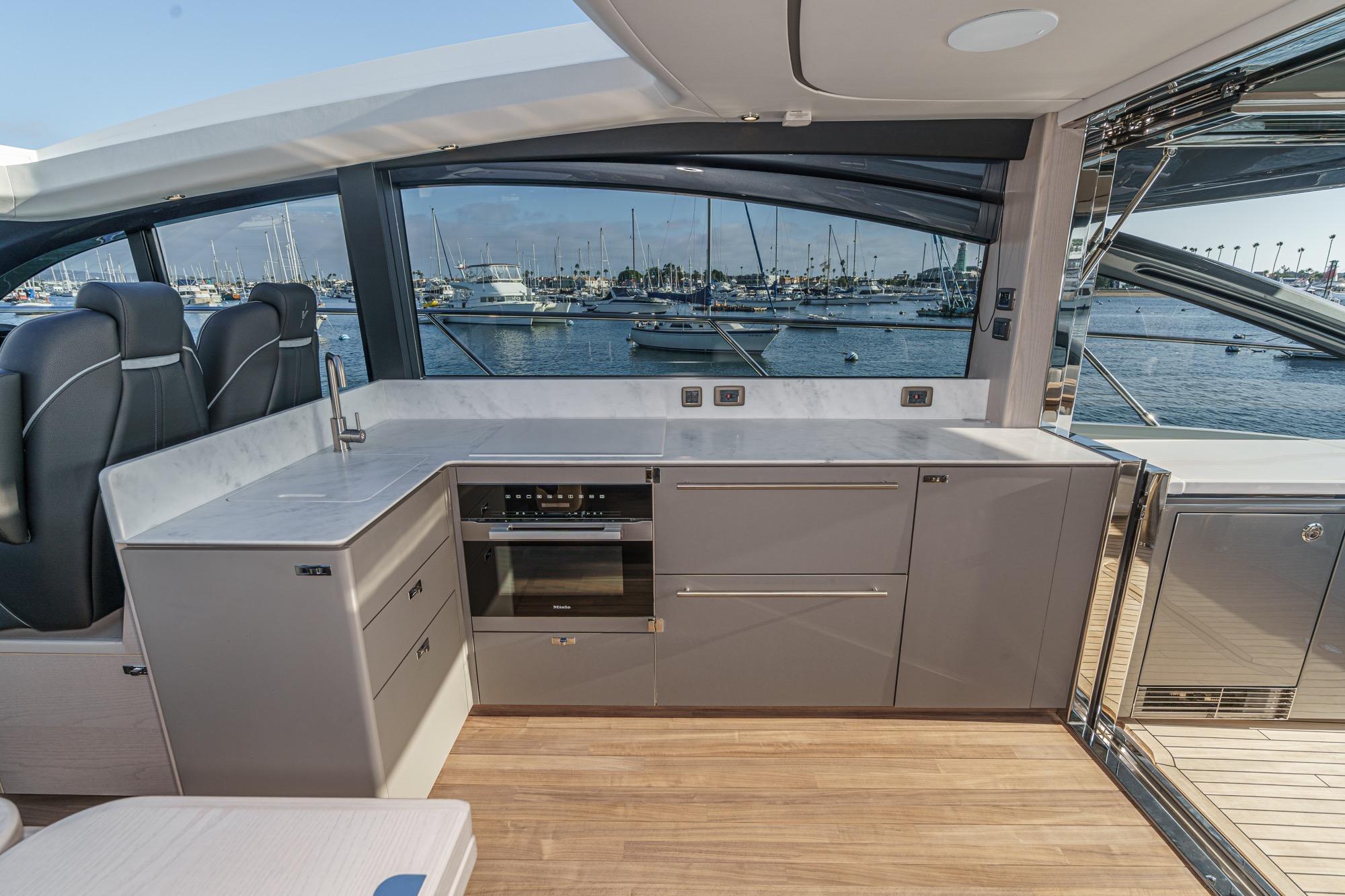 Luxurious interior of 2026 Princess V55 yacht with modern kitchen and scenic marina view.