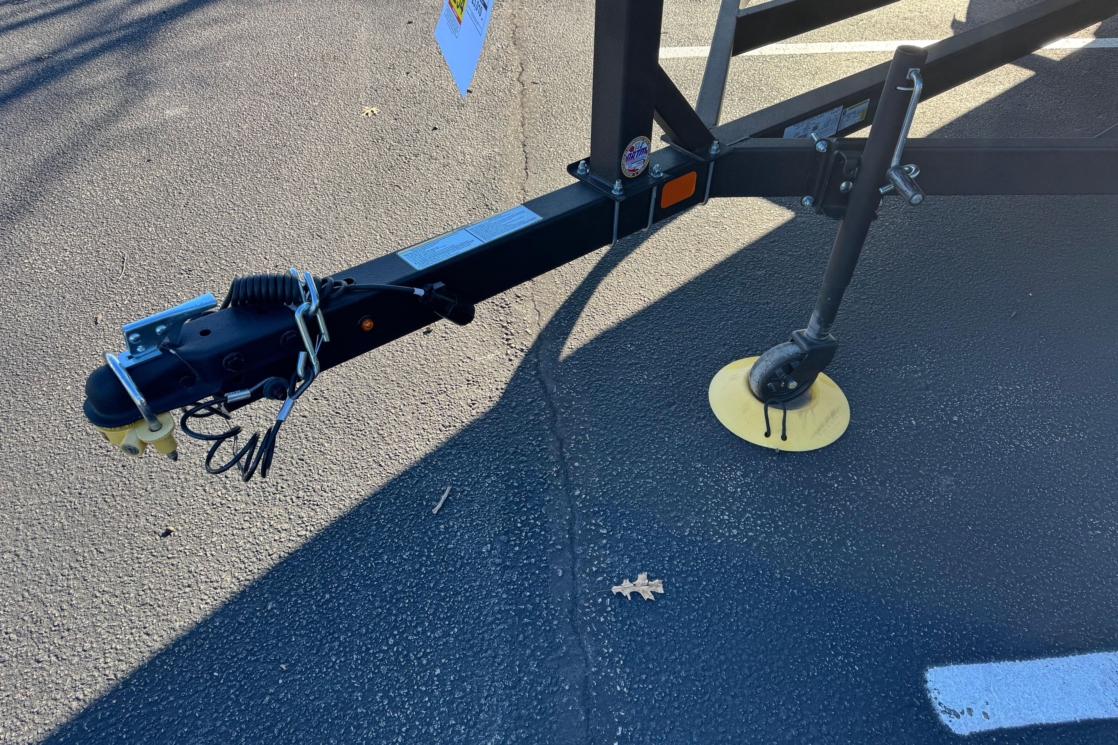 Trailer hitch and wheel of 2026 Tracker Grizzly 2072 Utility on asphalt surface.