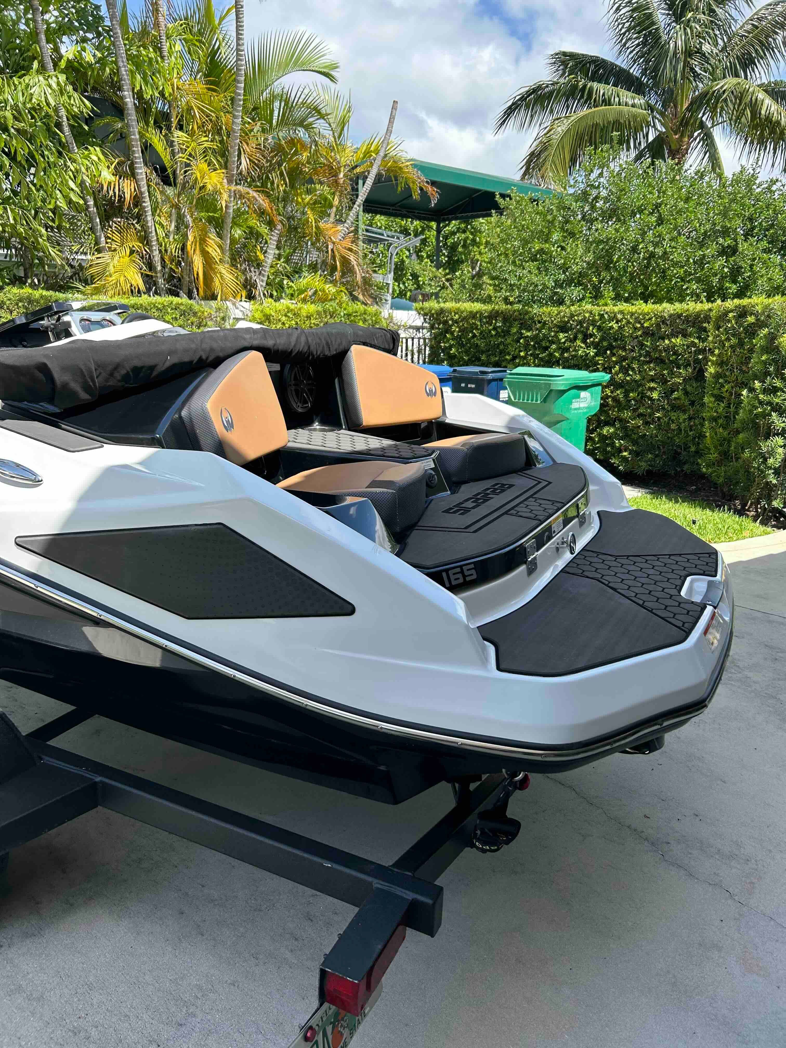 A 2022 Scarab 165 ID boat on a trailer, surrounded by tropical plants.