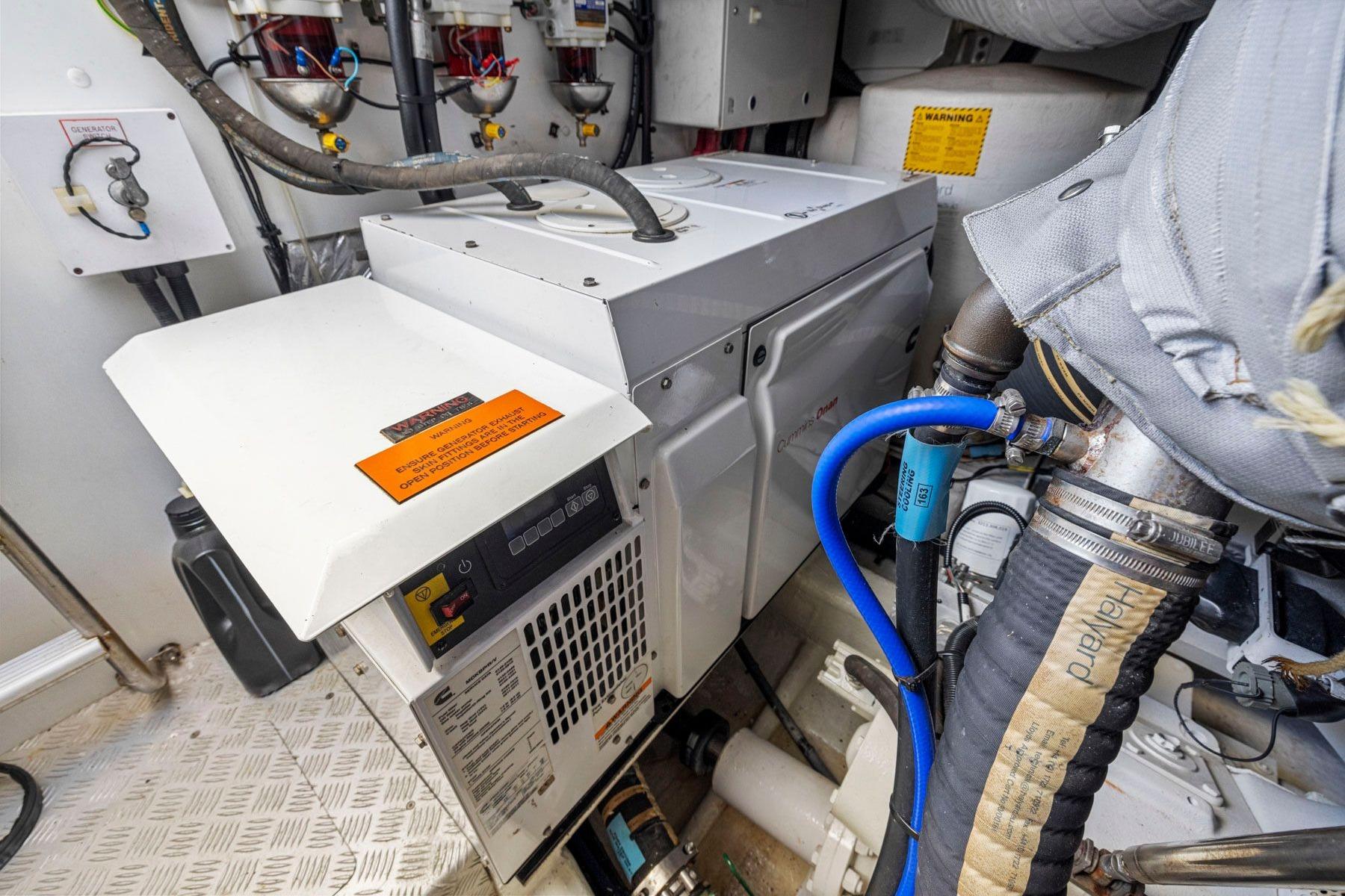 Engine room of 2015 Princess 60 Flybridge Motor Yacht, featuring generator and hoses.