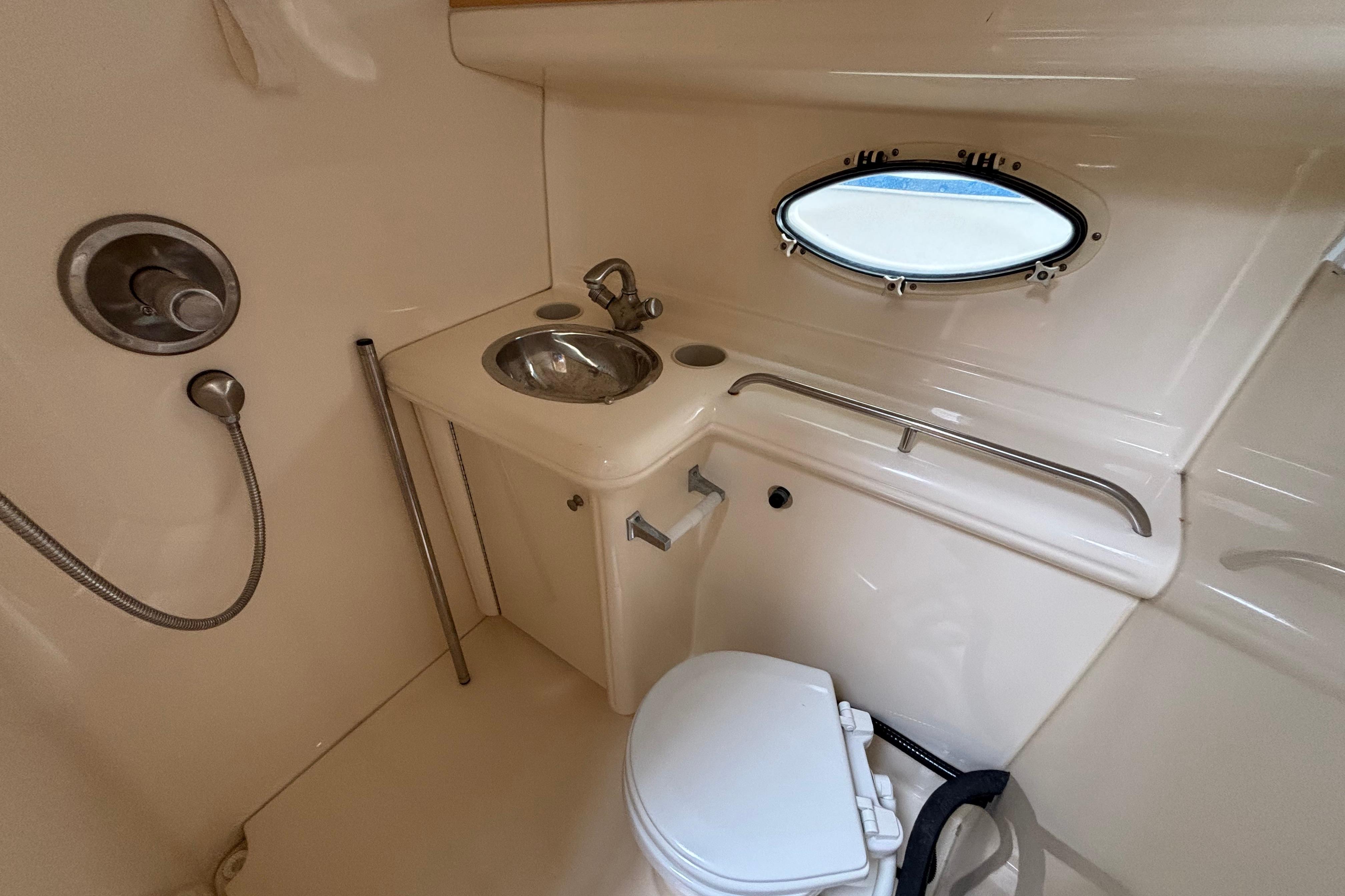 2004 Larson 310 boat bathroom with sink, toilet, and porthole window.