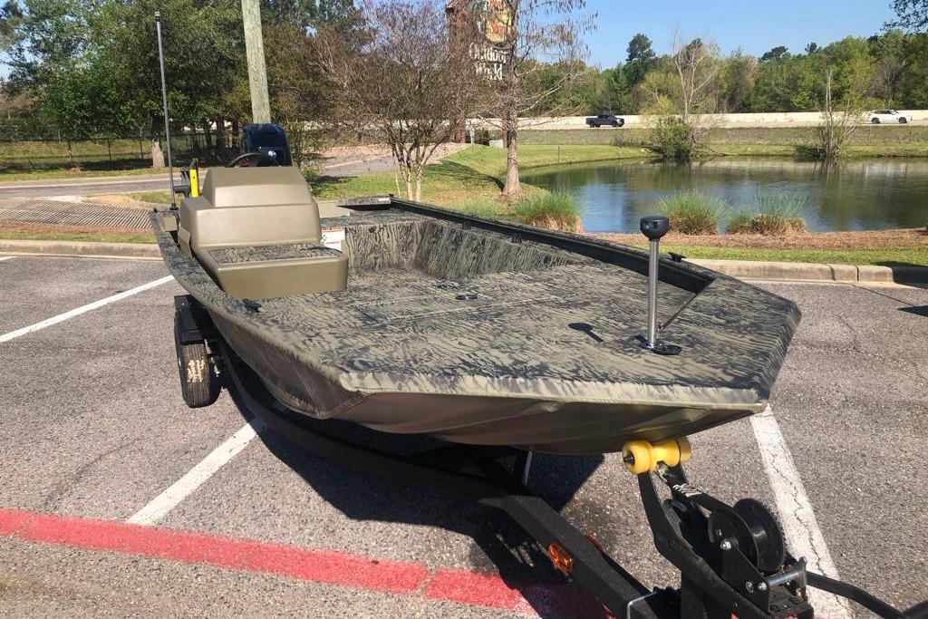 2026 Tracker Grizzly 1648 SC boat on trailer in parking lot near pond.