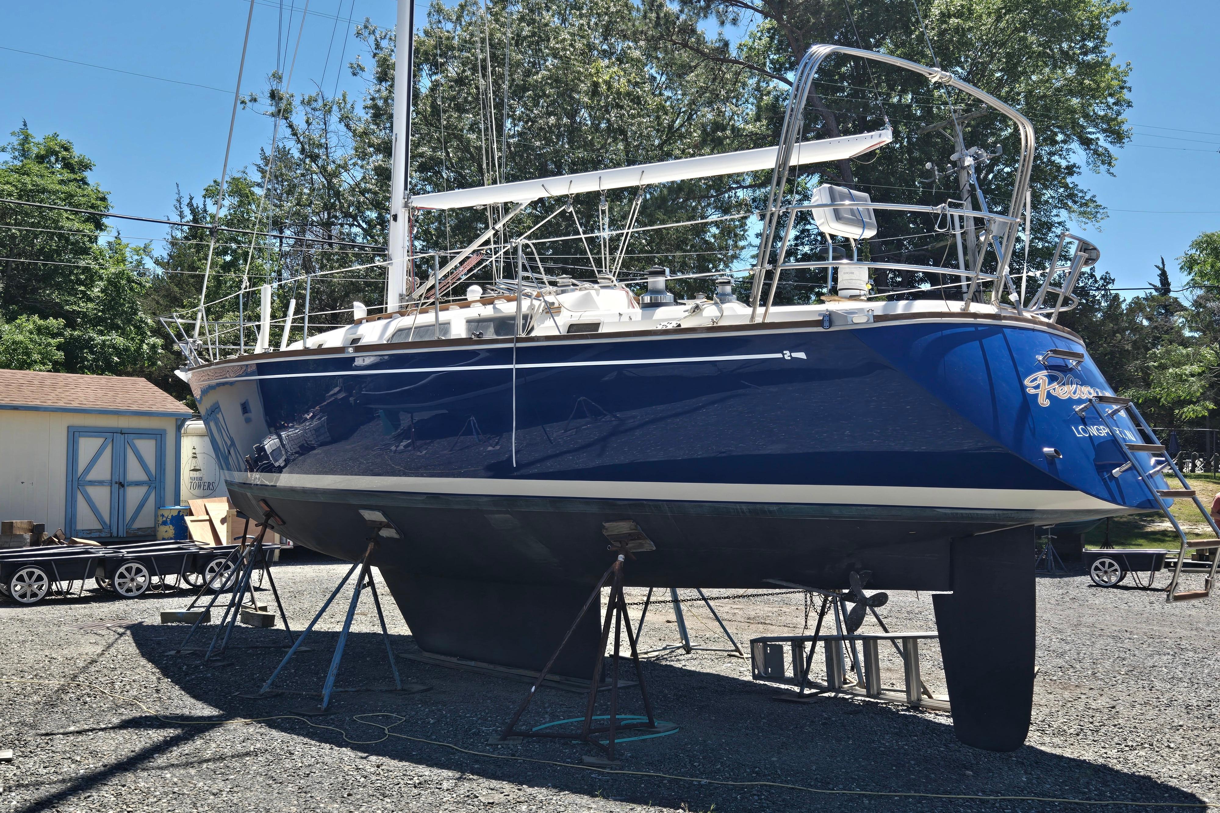 1988 Sabre 38 sailboat on stands, blue hull, outdoors, surrounded by trees and buildings.
