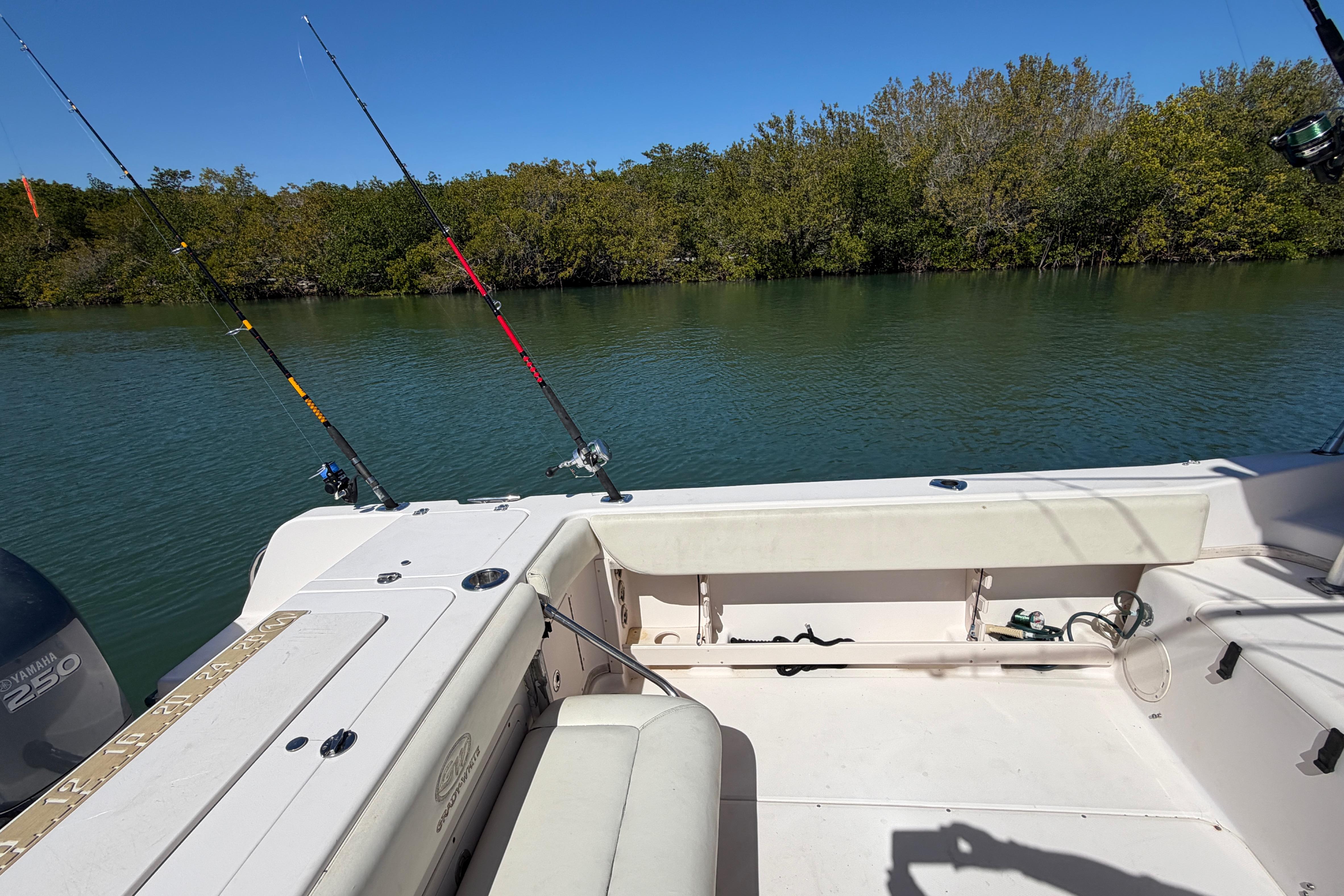 2006 Grady-White Sailfish 282 boat with fishing rods, calm water, and lush greenery.