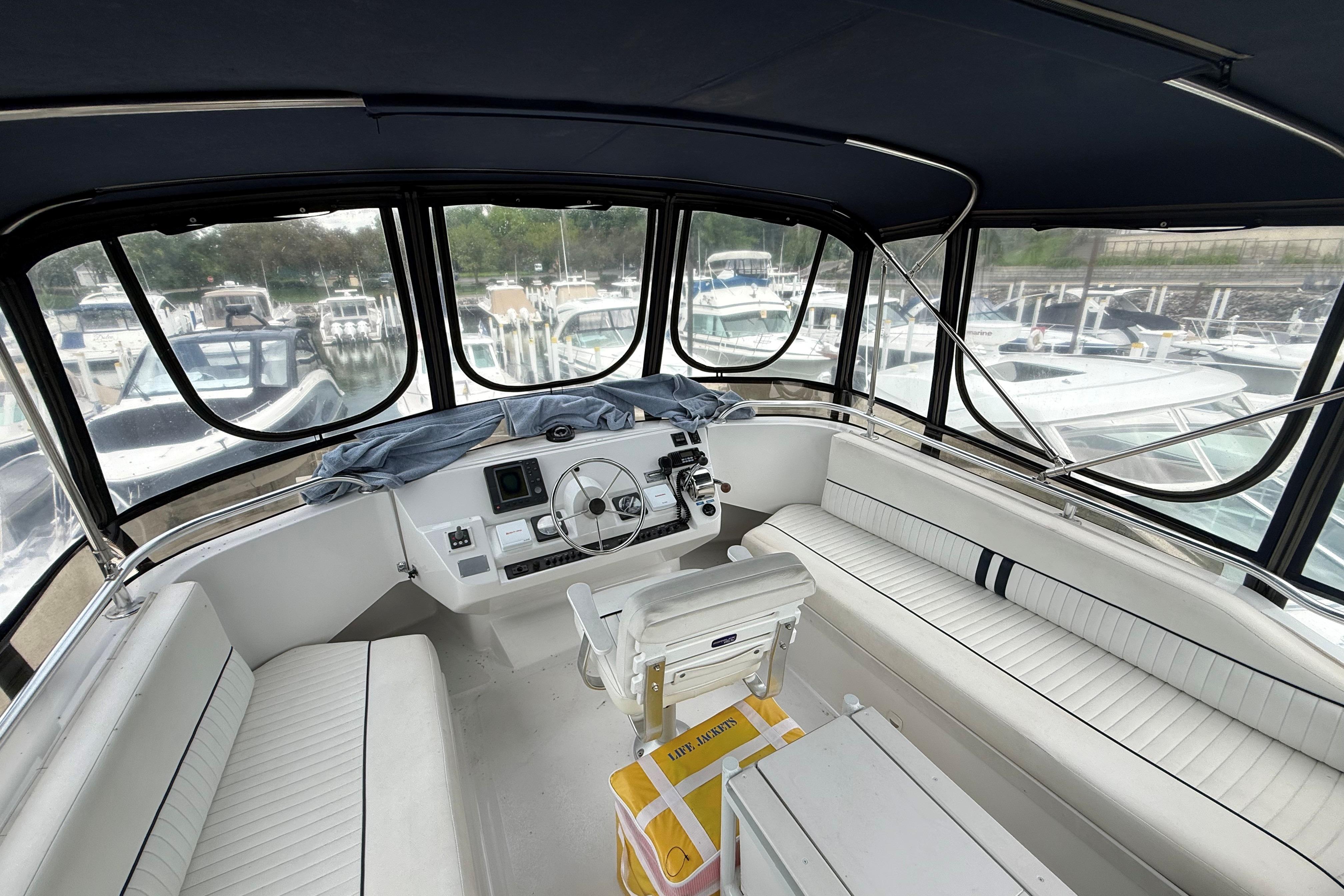 1999 Mainship 350 Trawler interior with helm, seating, and marina view.