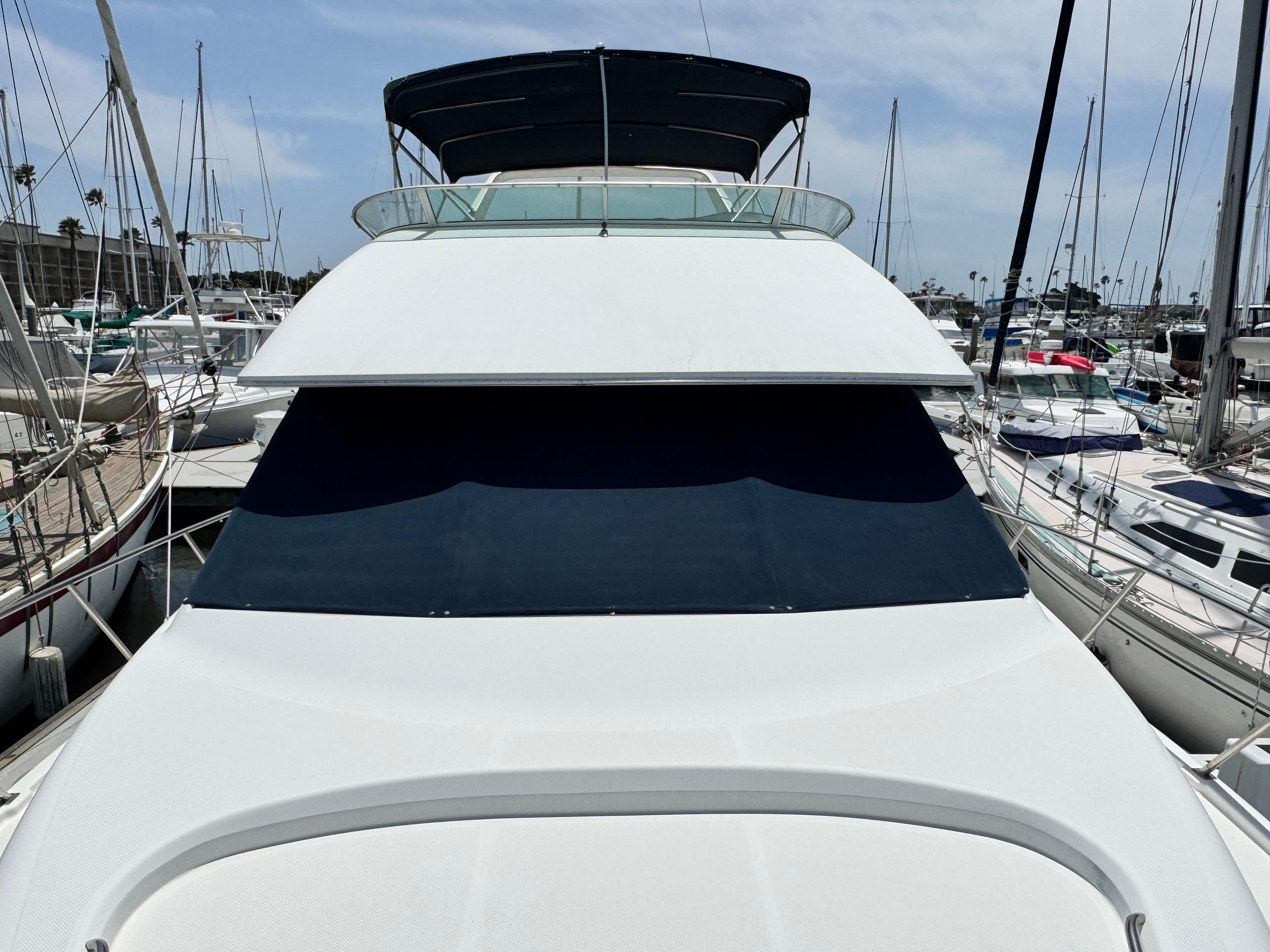 Bayliner 3988 yacht, 2000 model, docked in marina with sailboats in background.