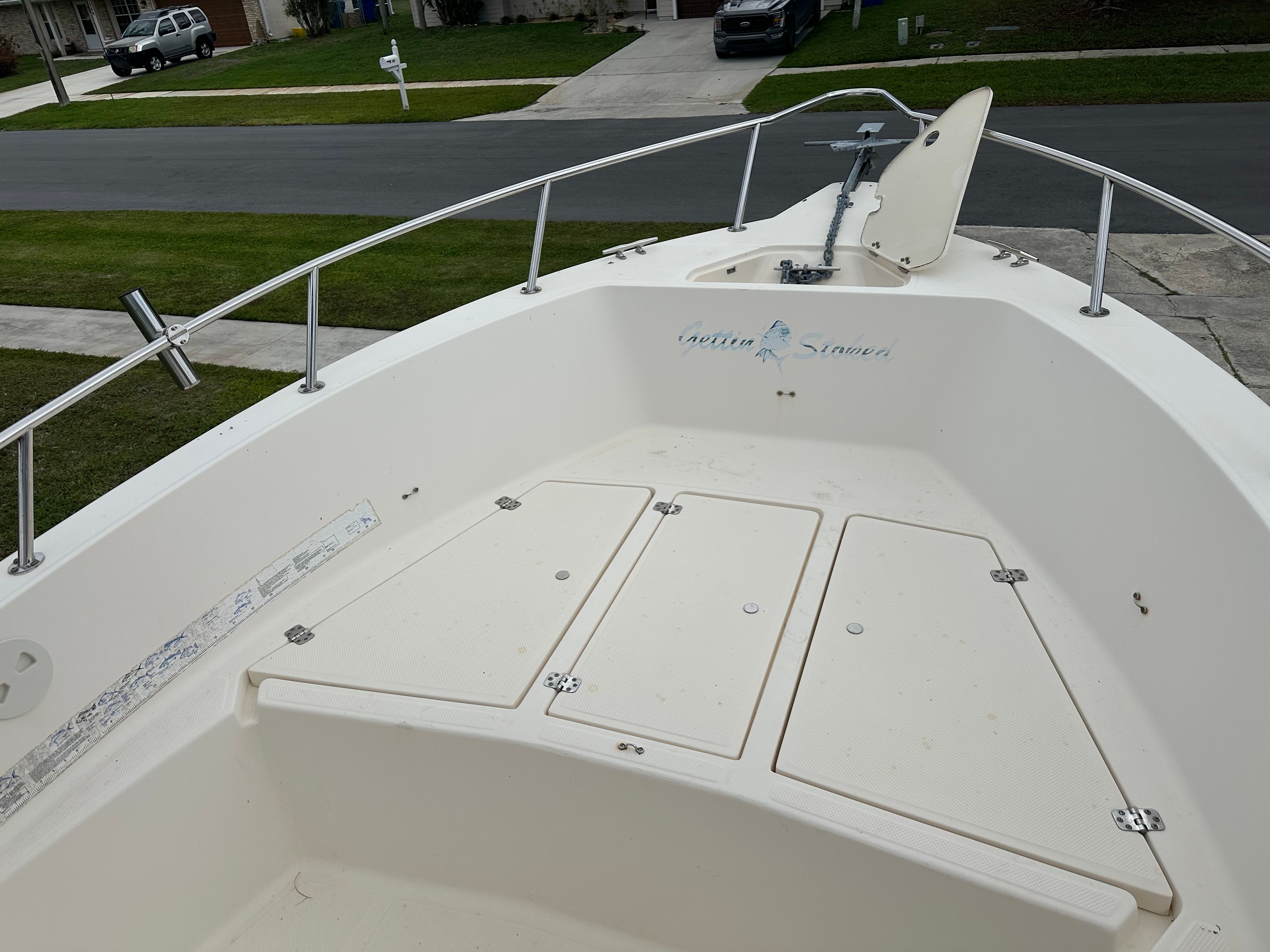 The boat features an open deck with storage hatches and stainless steel railings.