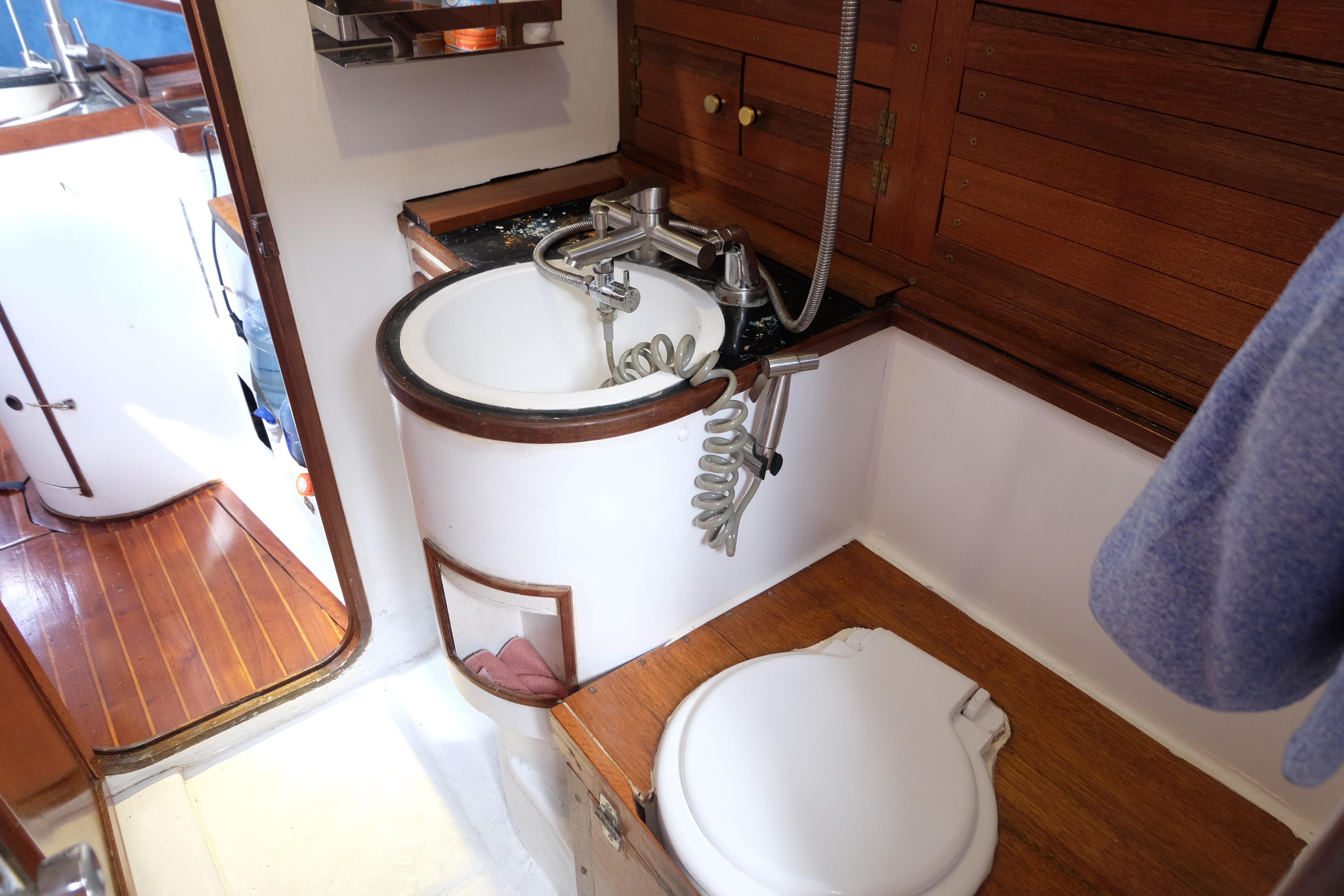 Compact bathroom in 1986 Martzcraft 35 yacht with wooden accents and round sink.