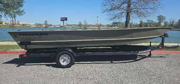 2025 Tracker GRIZZLY 2072 Utility boat on trailer by a lake.