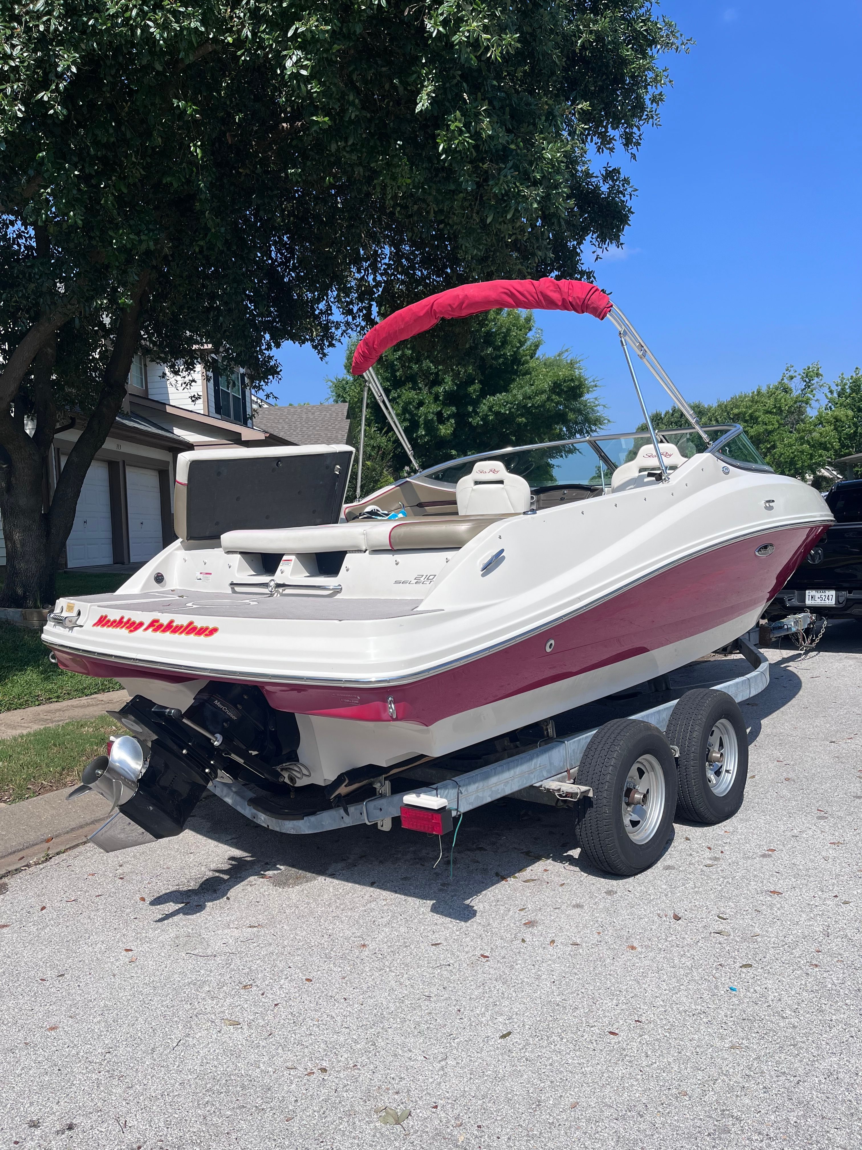 A 2007 Sea Ray 210 Select boat on a trailer, featuring a red sunshade.