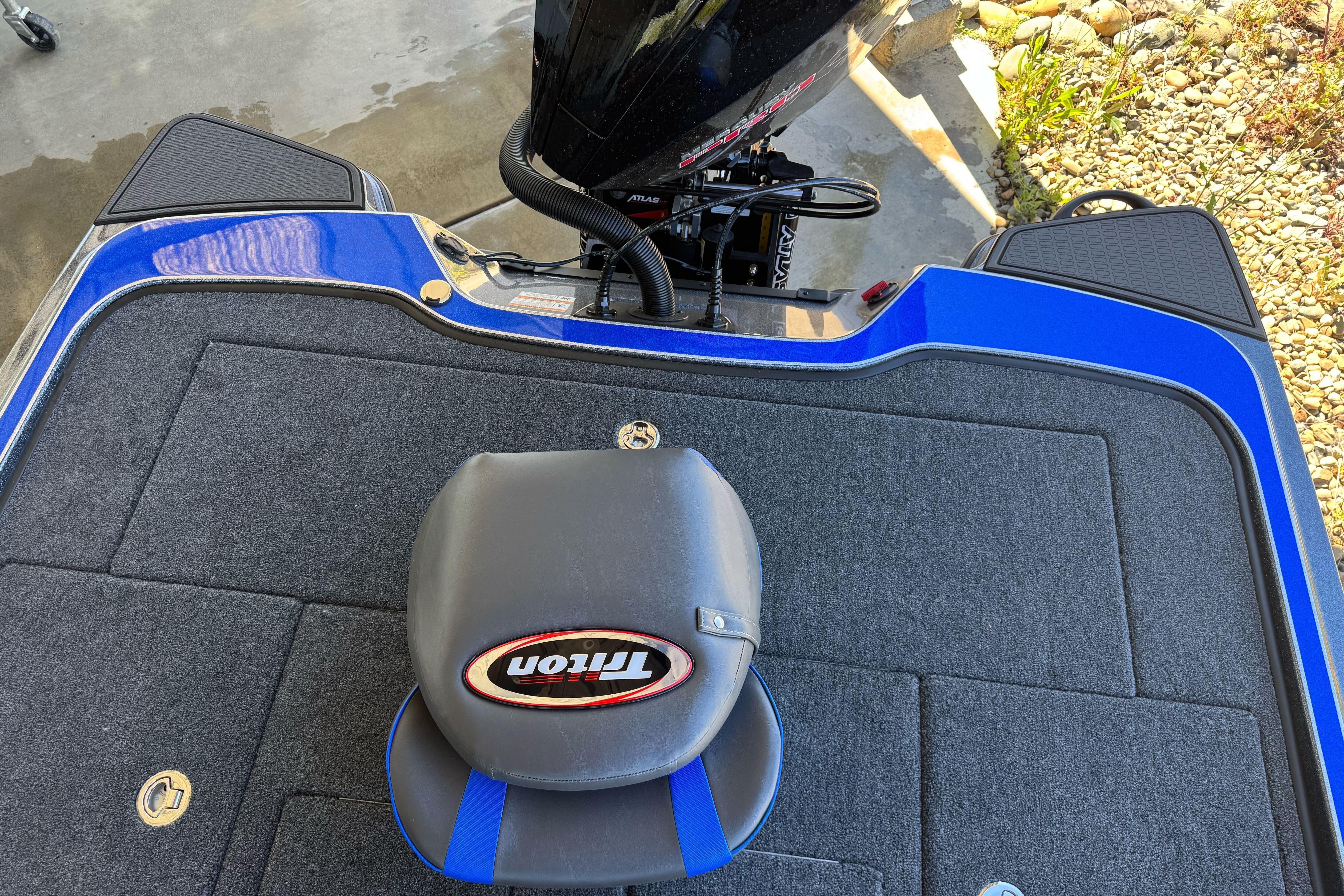 2026 Triton 21XP Patriot boat deck with seat and motor, featuring blue accents.