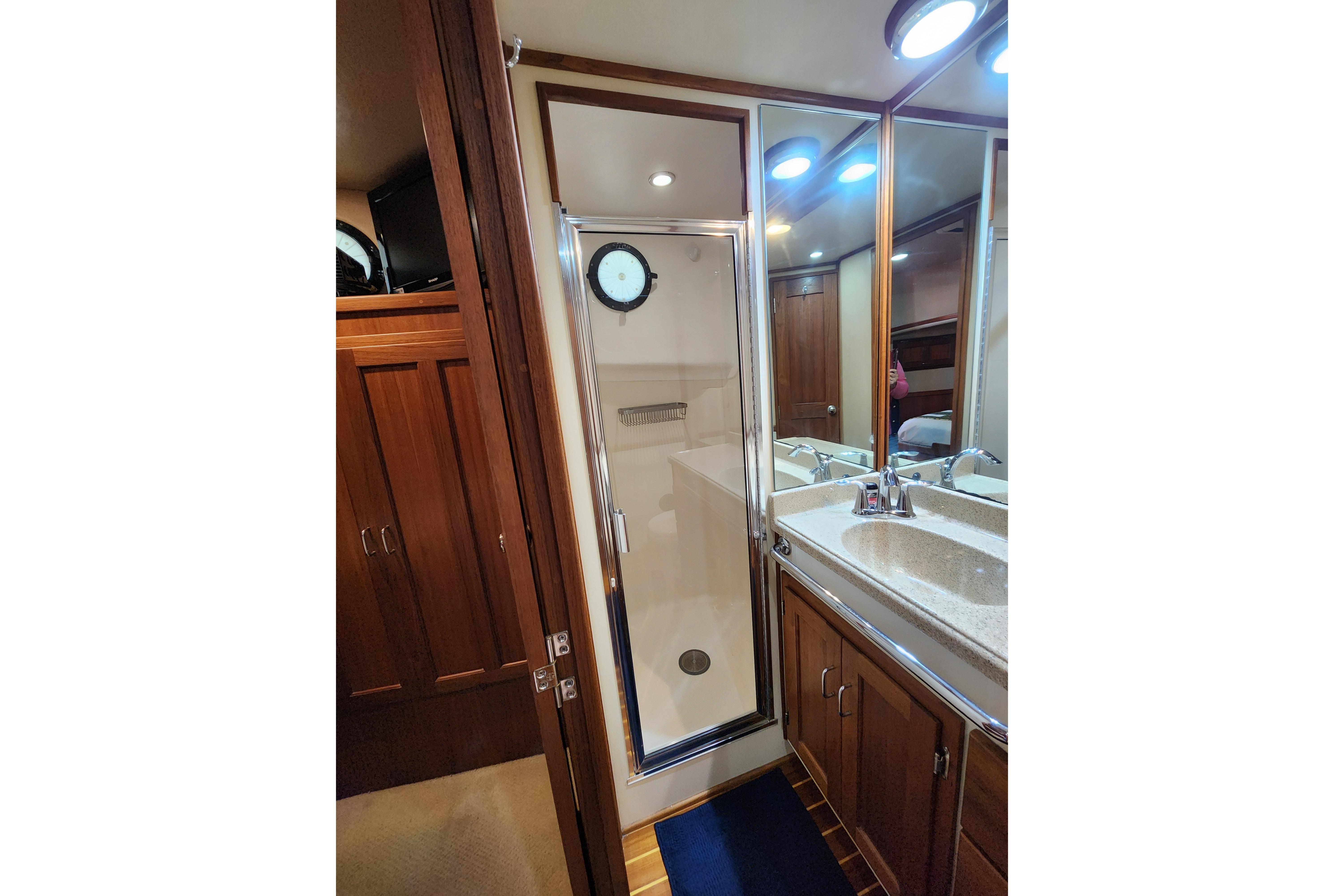 Luxurious 2006 American Tug AT bathroom with shower, wooden cabinets, and mirrored vanity.