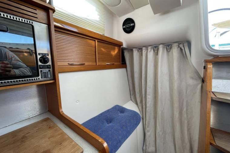 Interior of 2008 Dragonfly 35 Ultimate sailboat with microwave, wooden cabinets, and blue cushioned seat.