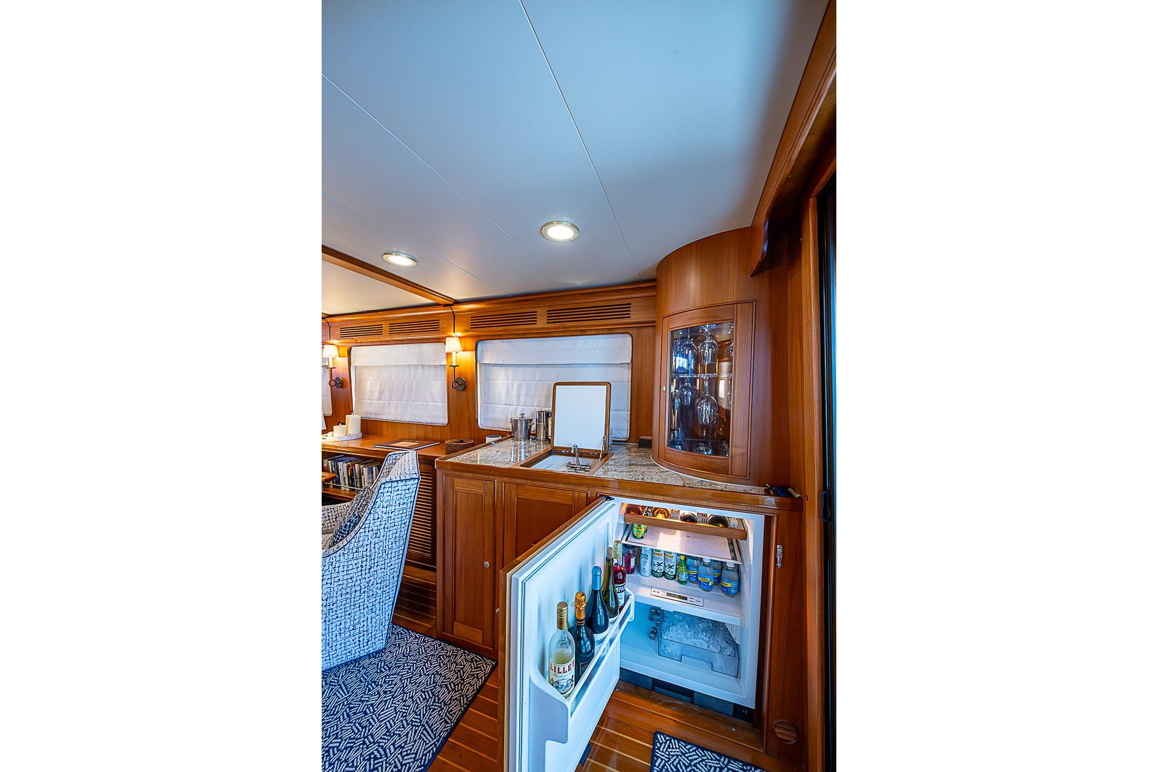 Luxurious interior of 2014 Marlow 80 Explorer yacht with open fridge and elegant wood finish.
