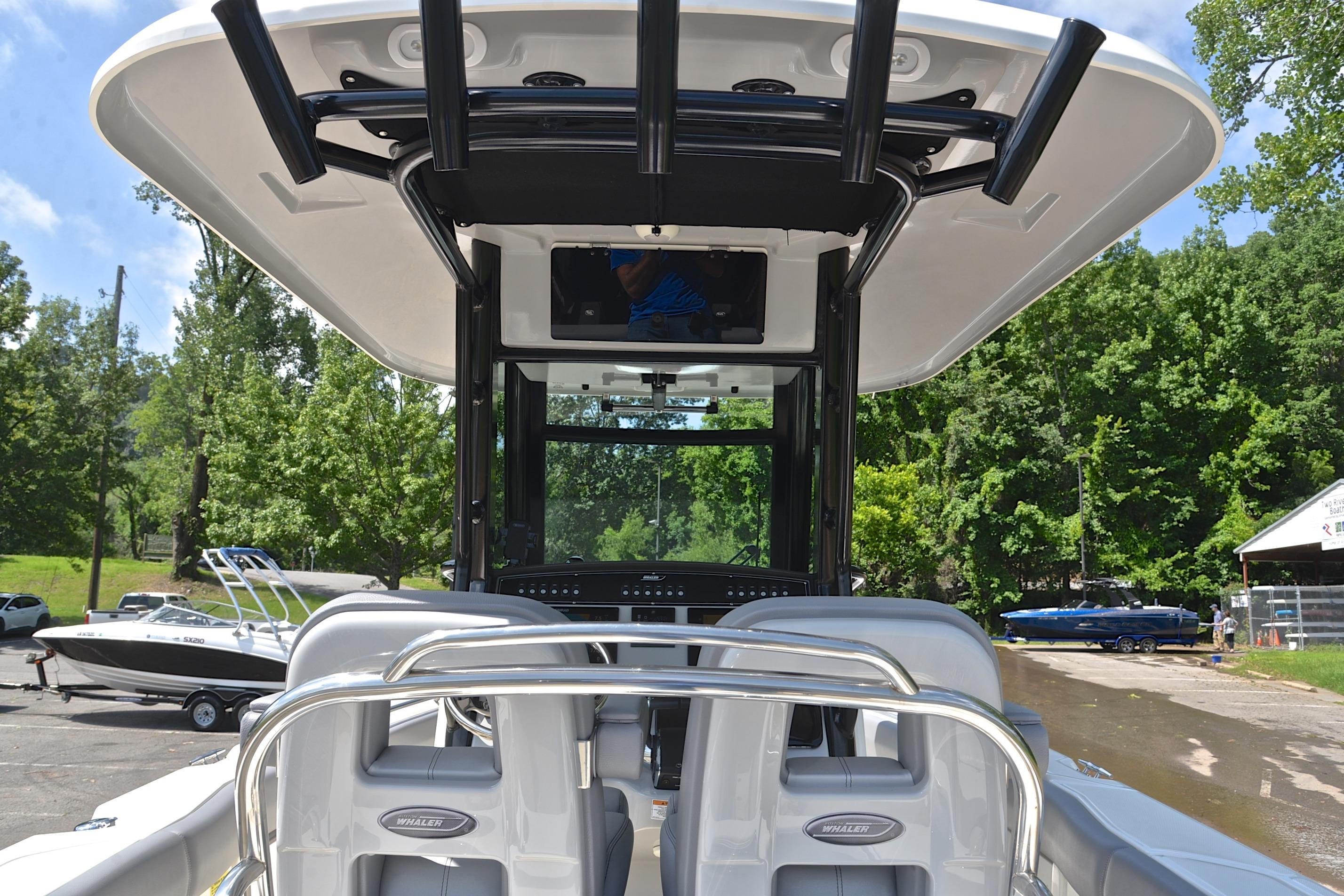 2024 Boston Whaler 250 Outrage boat interior with seating and console, surrounded by trees.
