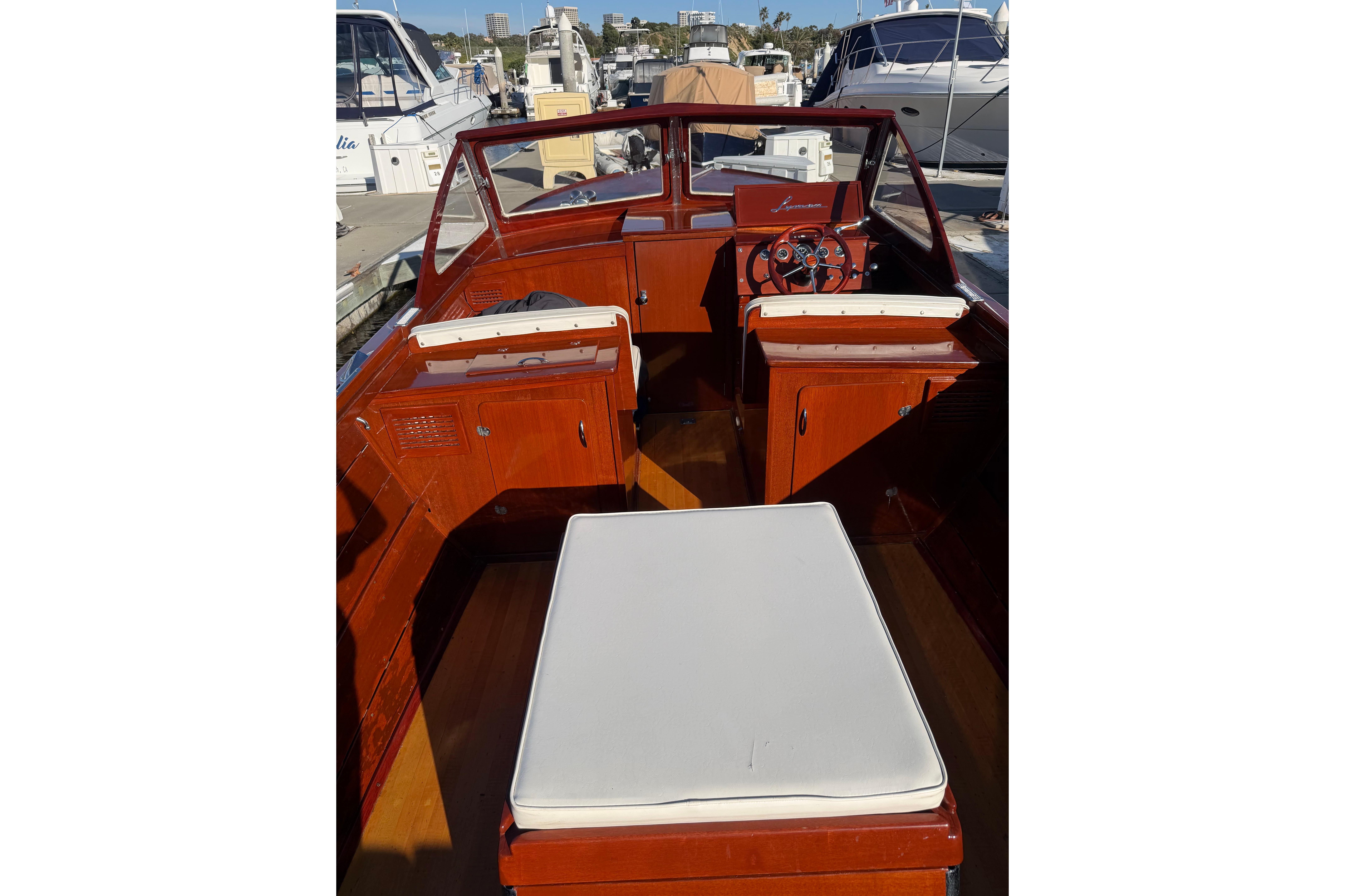 1964 Lyman 25 Sleeper boat interior with wooden finish and white seating at a marina.
