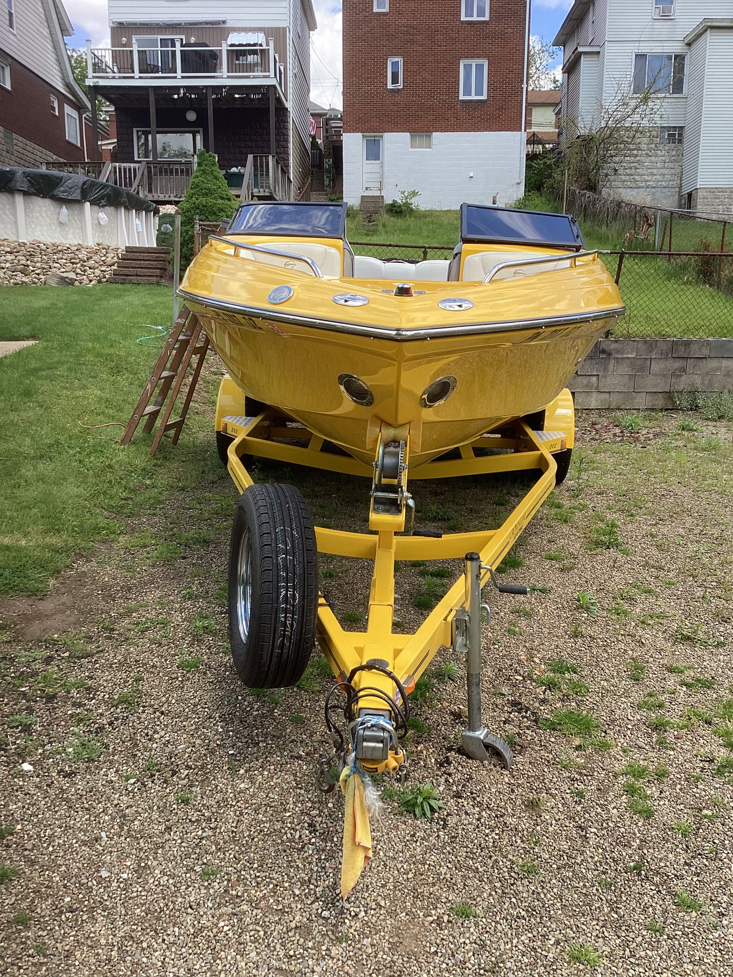 Yellow 2005 Crownline 202 BR LPX boat on trailer in yard.