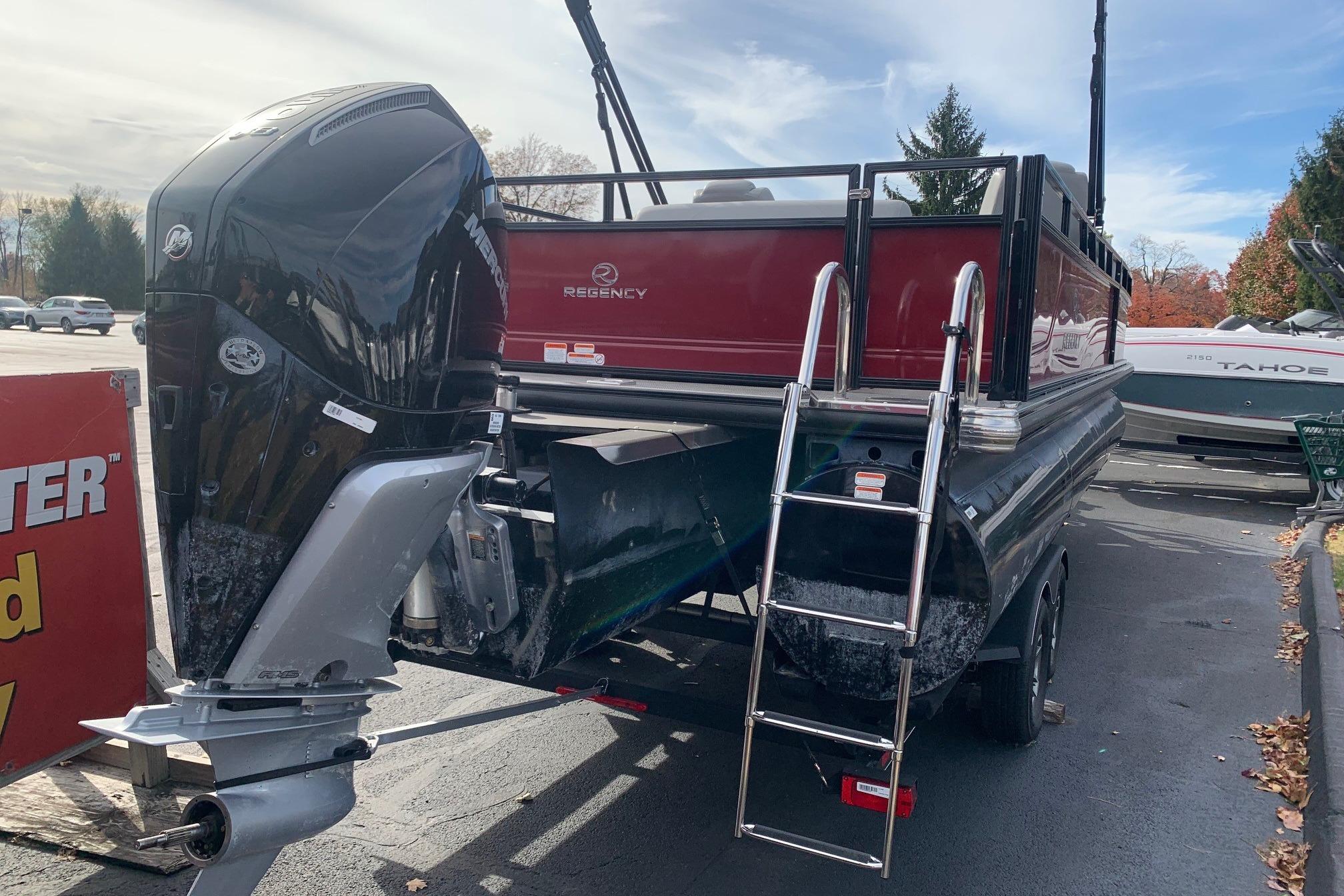 2024 Regency 250DL3 pontoon boat with outboard motor and ladder, parked outdoors.