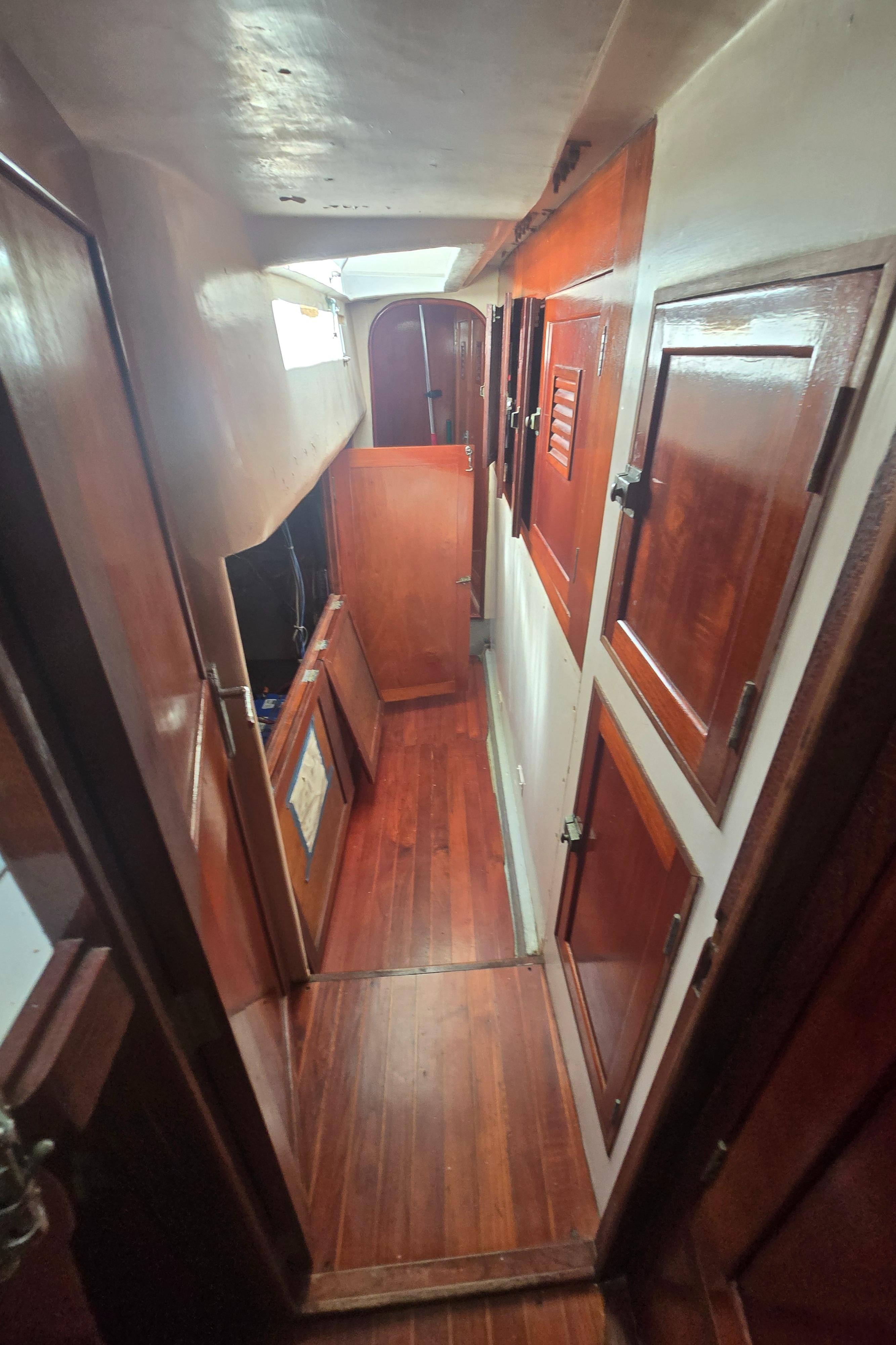 1978 Herreshoff 50 yacht interior with wooden paneling and narrow corridor.