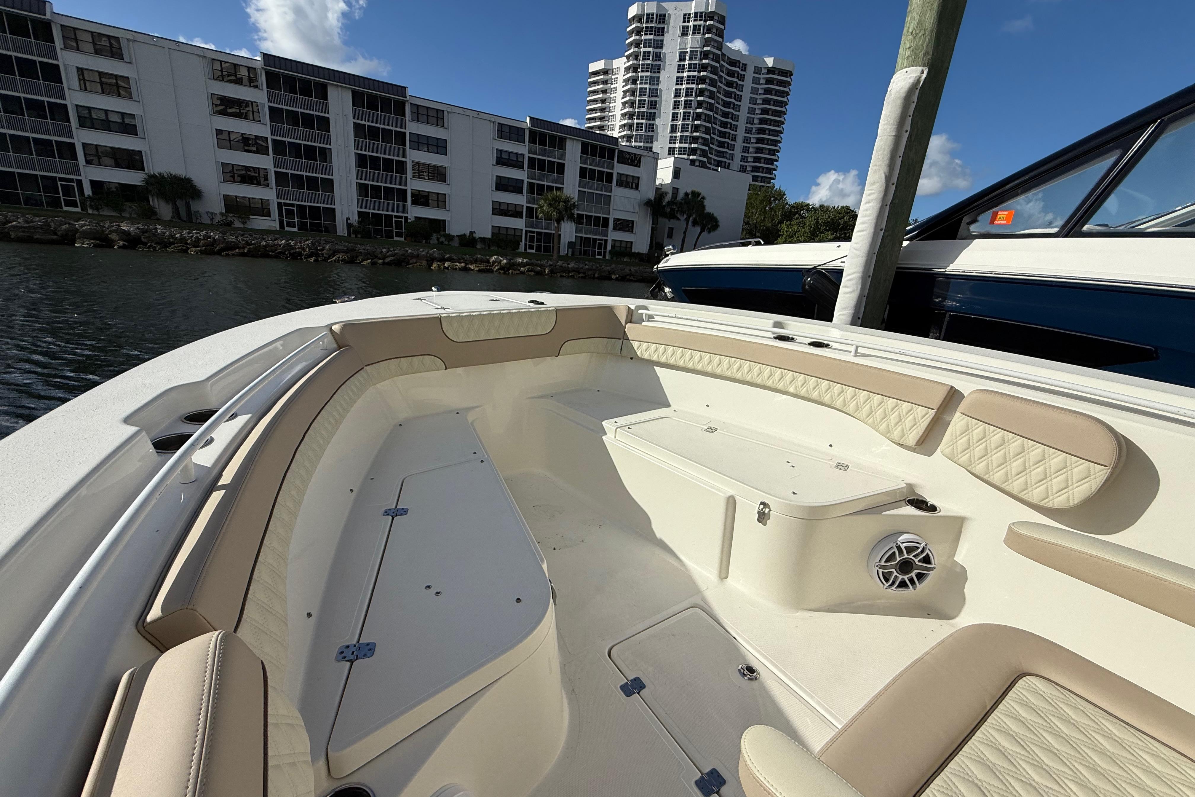 2018 NauticStar 28 XS boat interior with beige seating, docked near waterfront buildings.