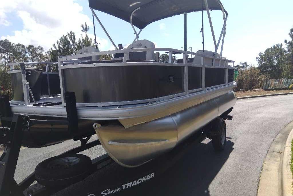 2026 Sun Tracker Bass Buggy 18 DLX pontoon boat on trailer, parked outdoors.