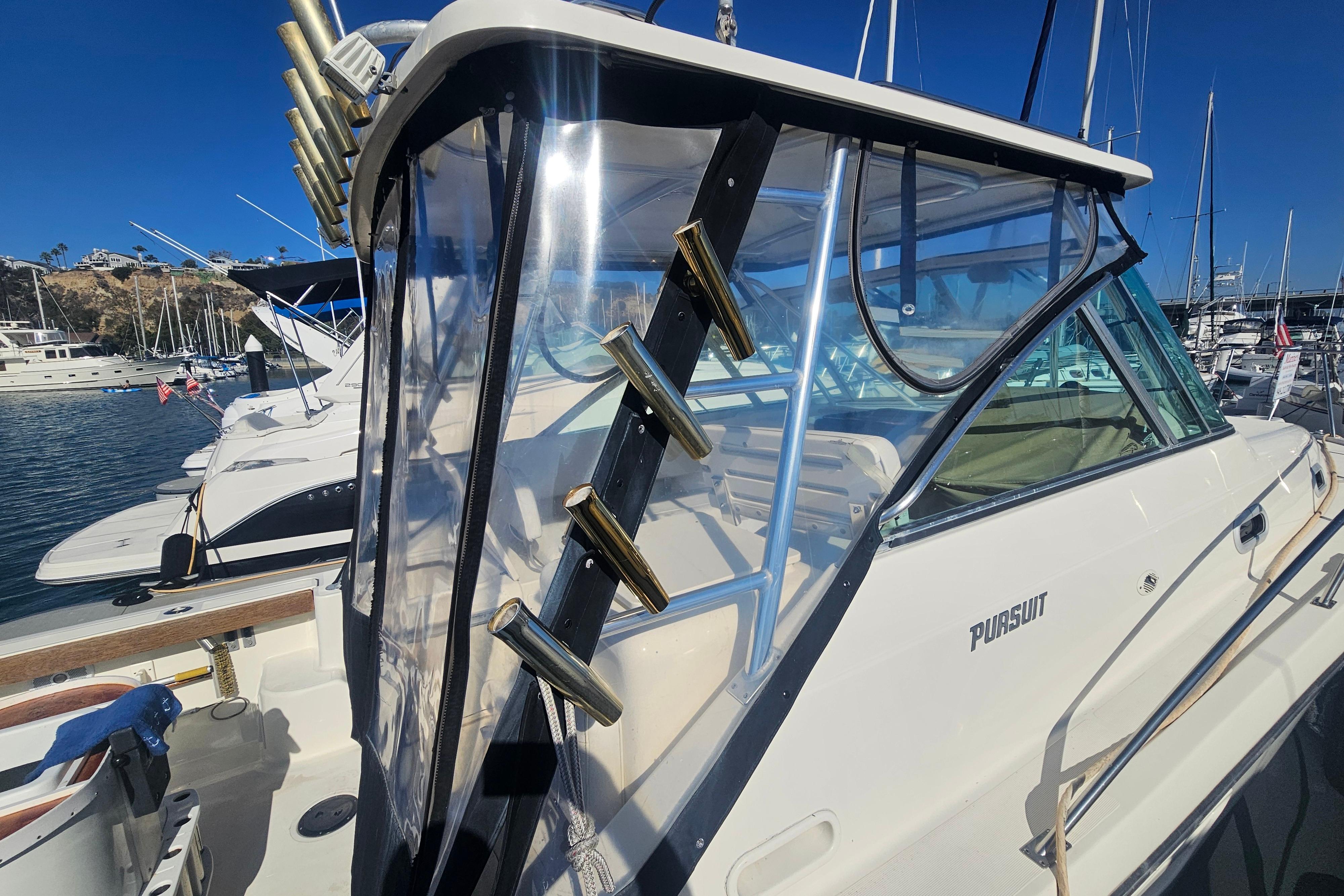 2001 Pursuit 3000 Express boat docked in marina, featuring clear enclosure and rod holders.