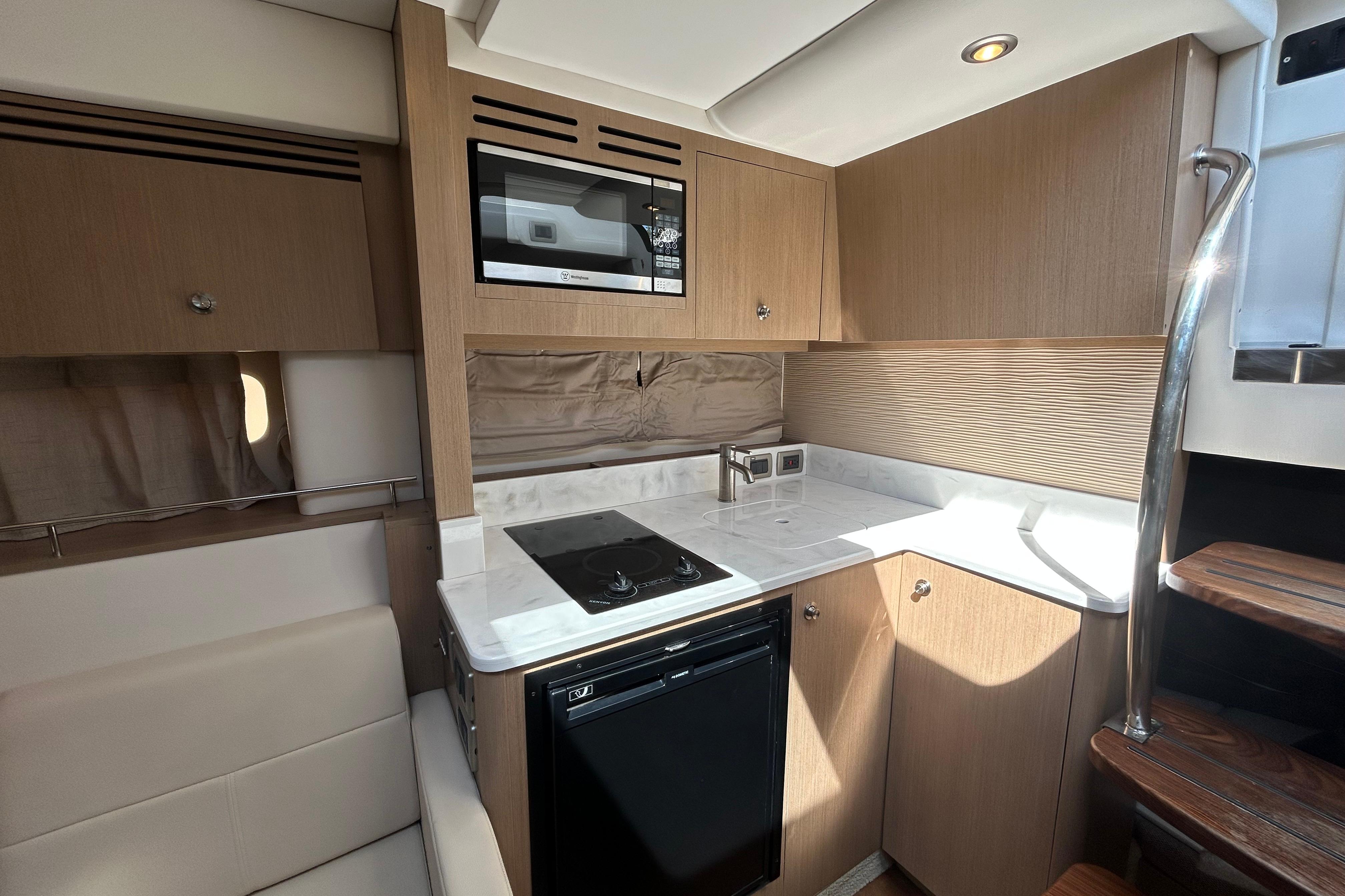 Modern kitchen interior of 2019 Sea Ray Sundancer 350 yacht with wood cabinetry and appliances.