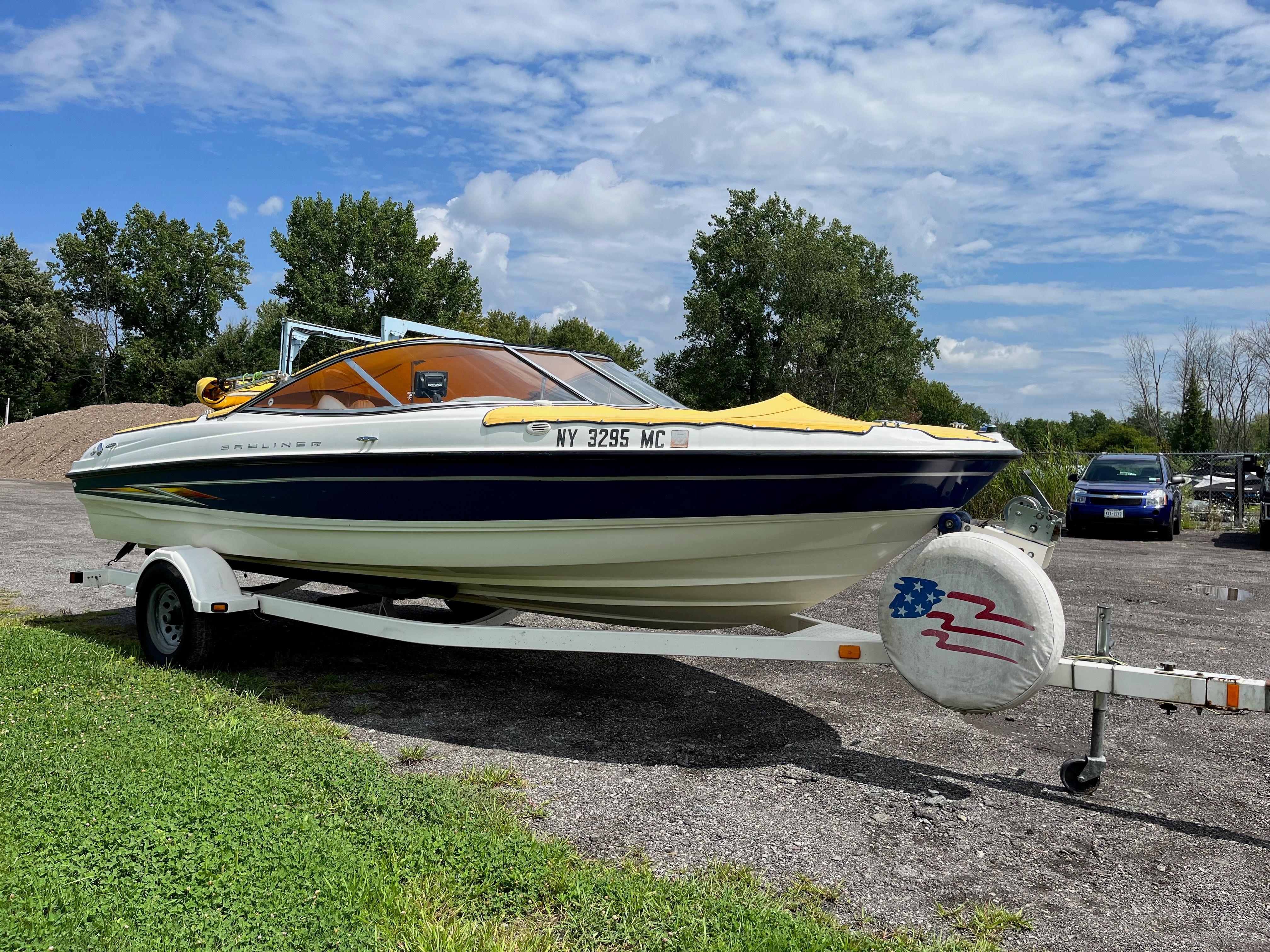 2005 Bayliner 205BR on a trailer, parked outdoors, with trees in the background.