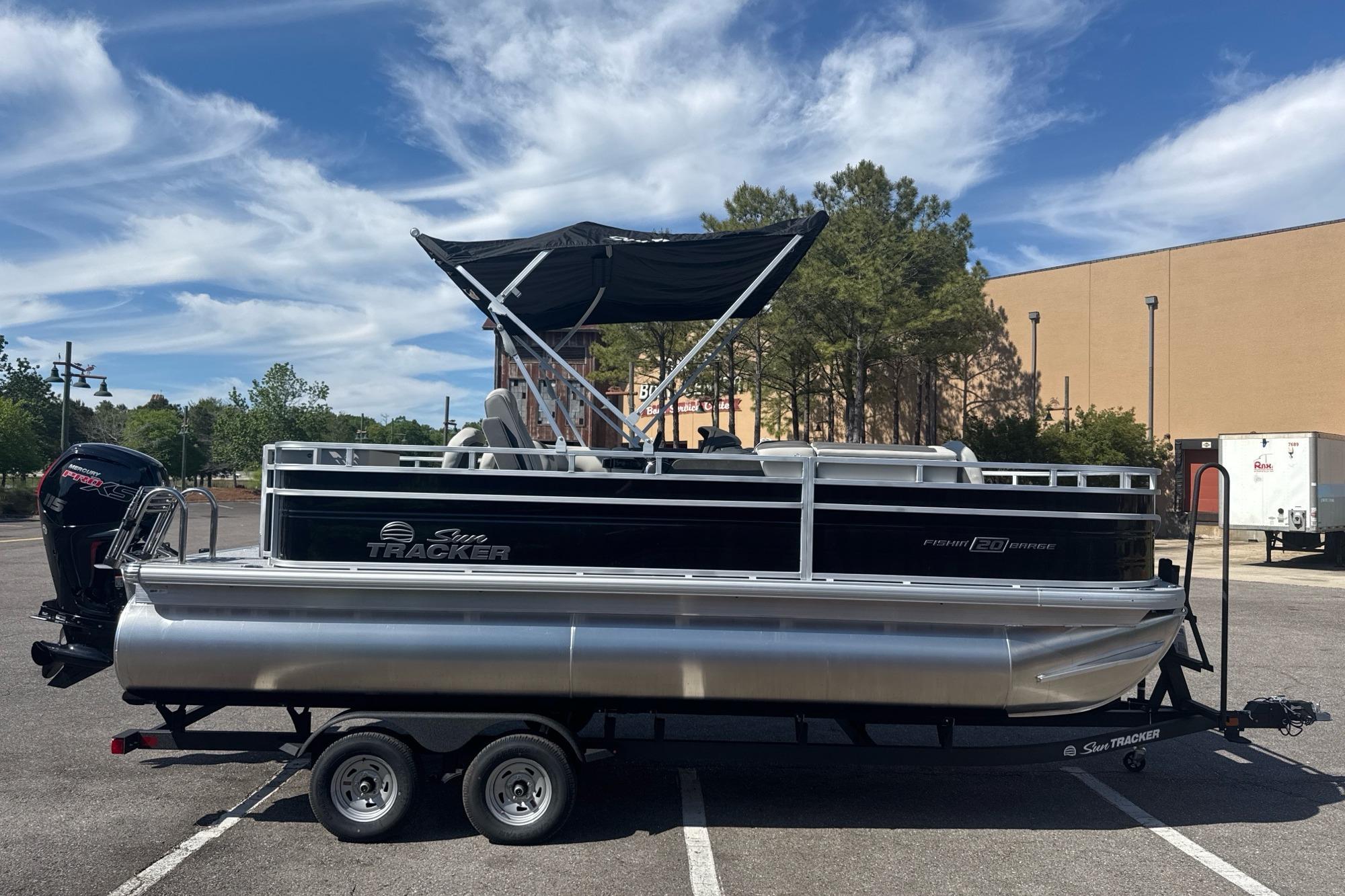 2026 Sun Tracker Fishin' Barge 20 DLX pontoon boat on trailer, parked outdoors.