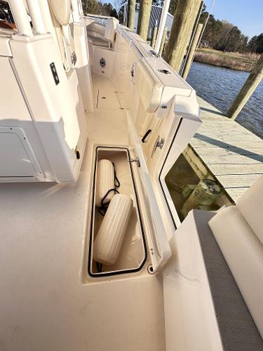 2023 Cobia 301 Center Console boat with open storage compartment at dock.