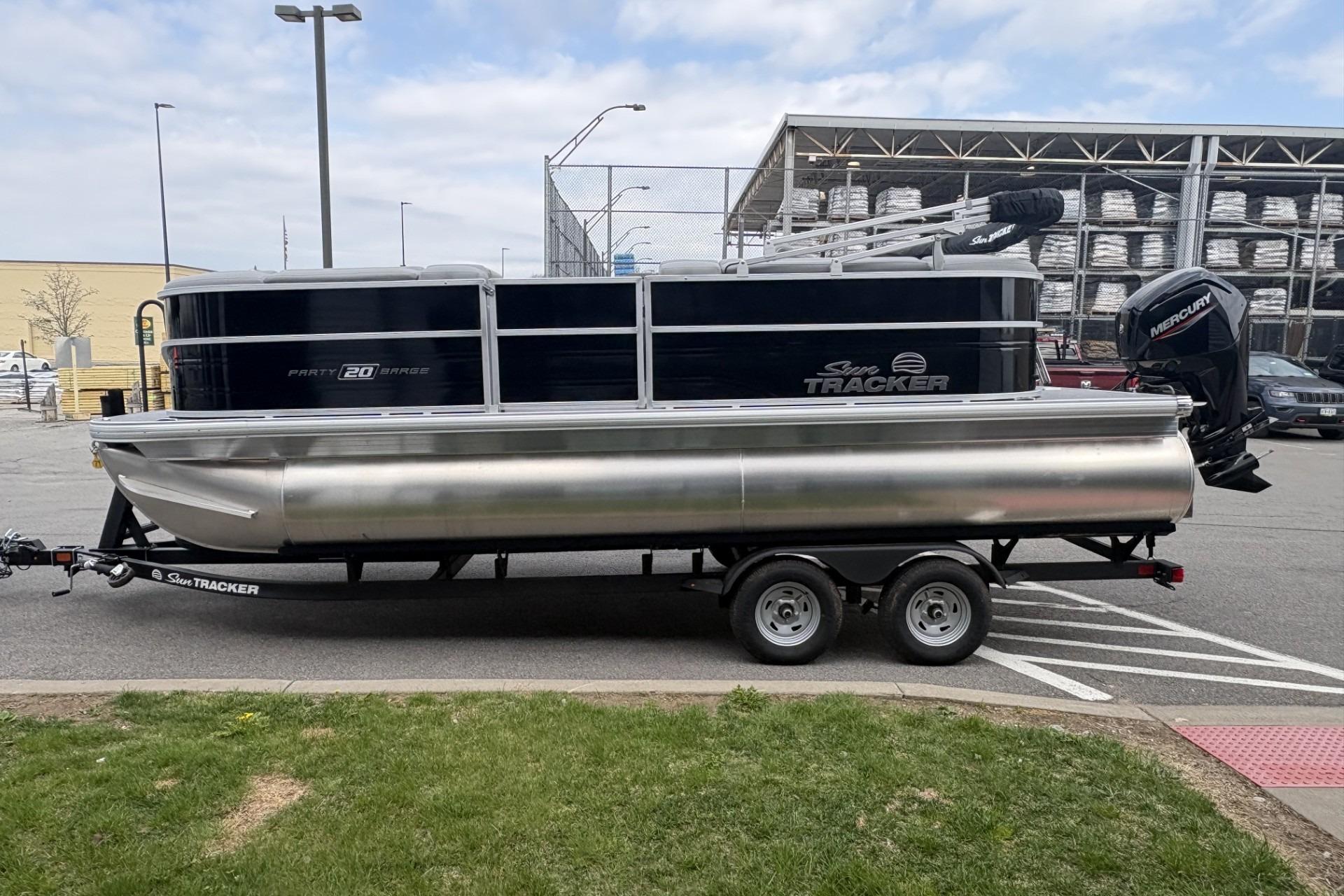 2026 Sun Tracker Party Barge 20 DLX pontoon boat on trailer in parking lot.