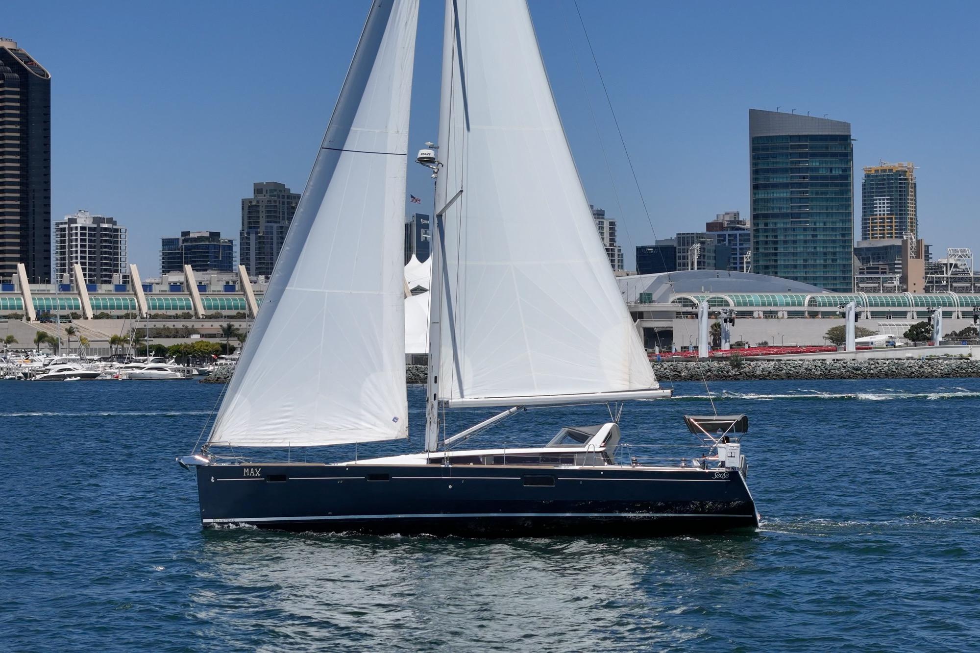 2017 Beneteau Sense 50 sailboat cruising near city skyline on a sunny day.