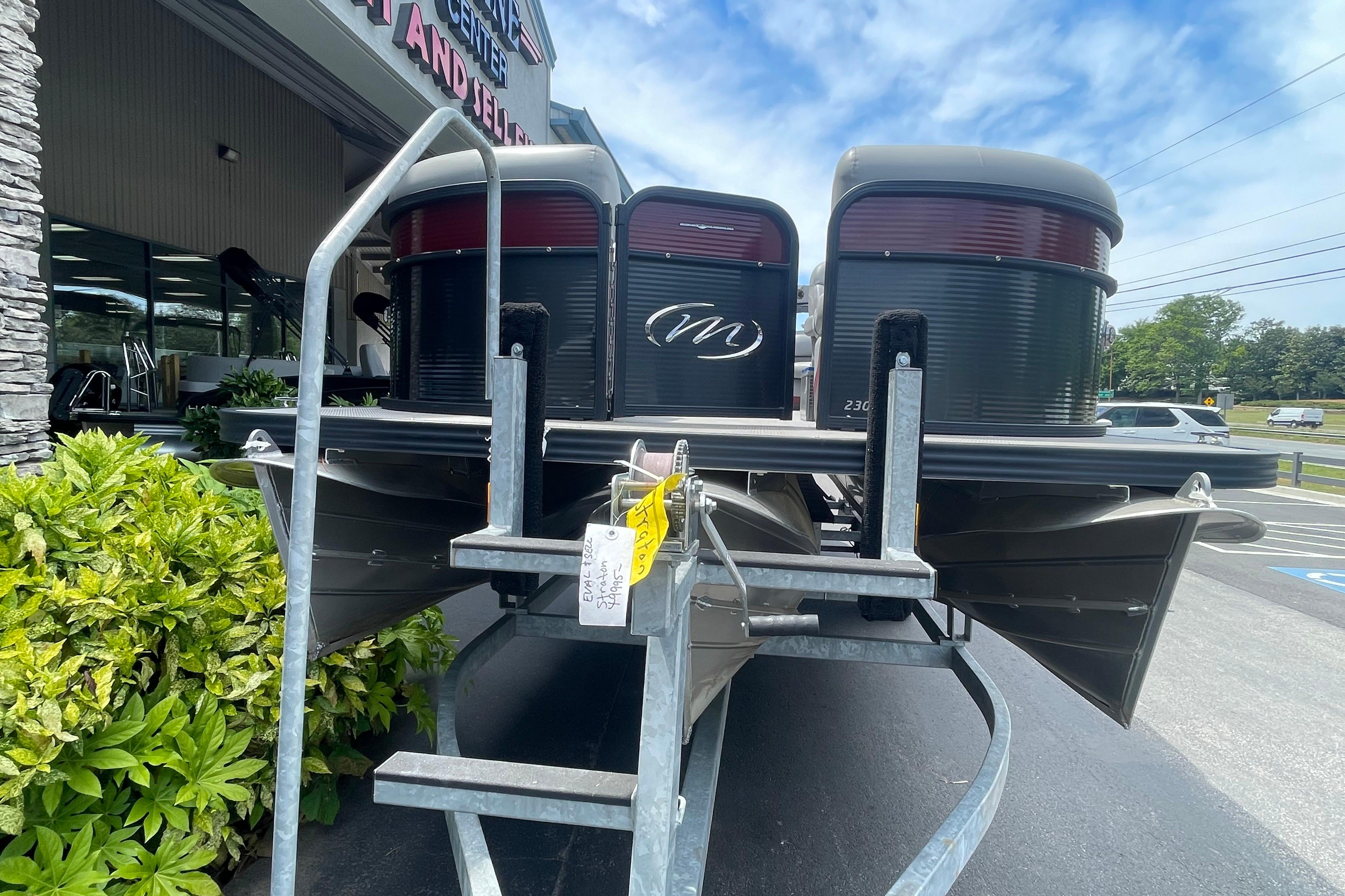 2022 Manitou 23 Oasis pontoon boat on trailer, dealership background.