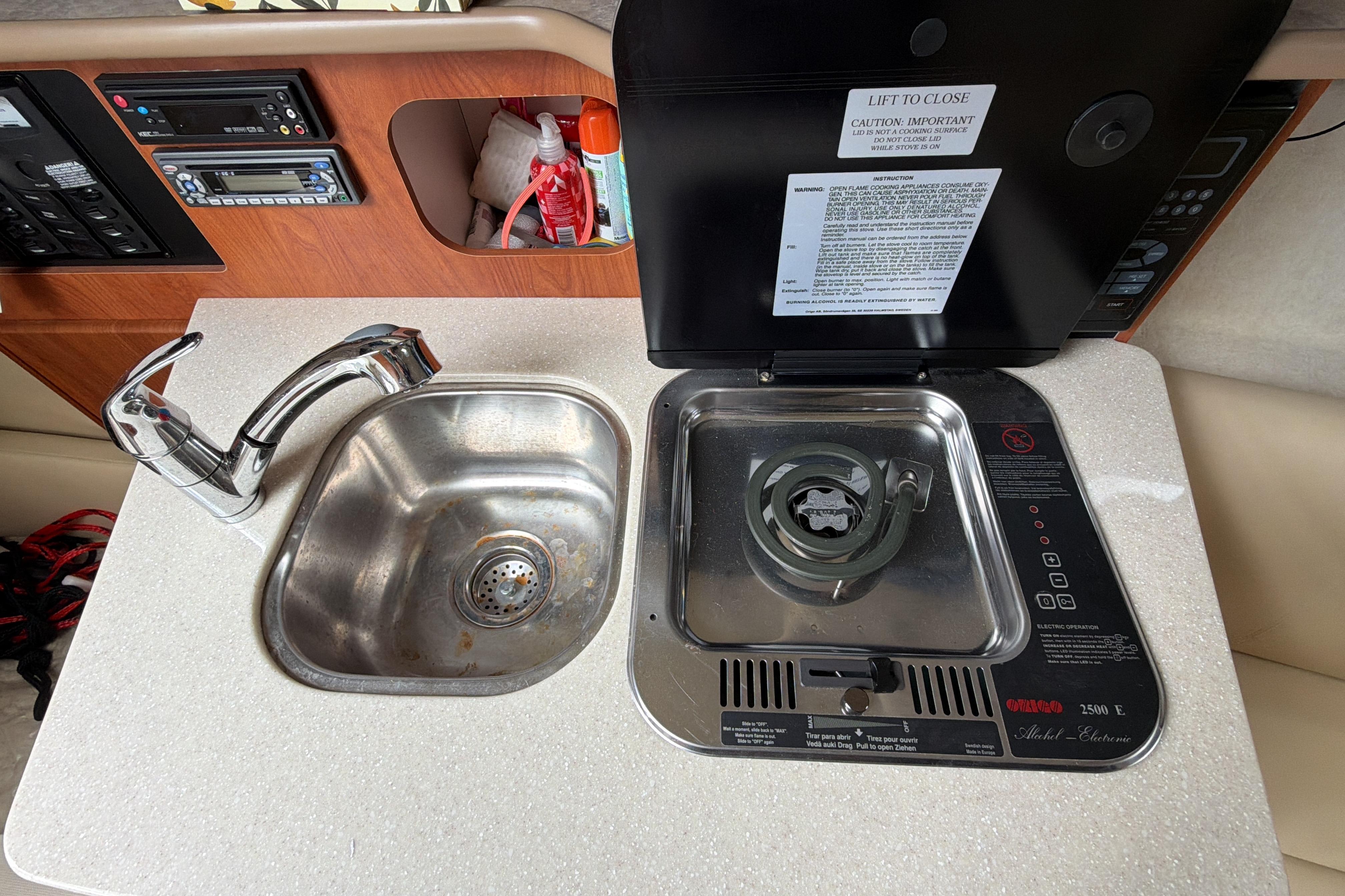 2007 Bayliner 245 boat kitchenette with sink and stove, featuring control panels and storage.