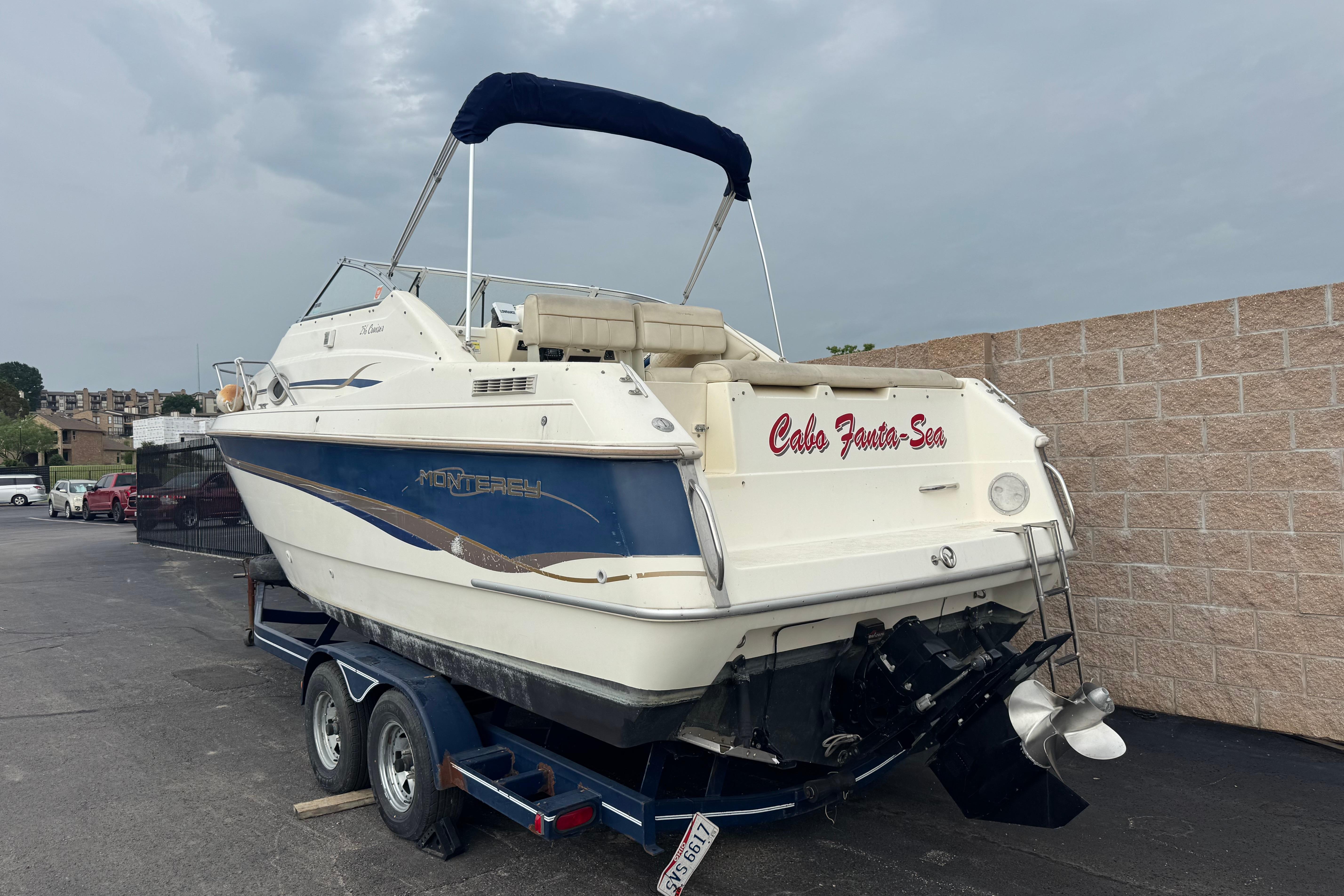 1997 Monterey 256 Cruiser boat on trailer, parked outdoors.