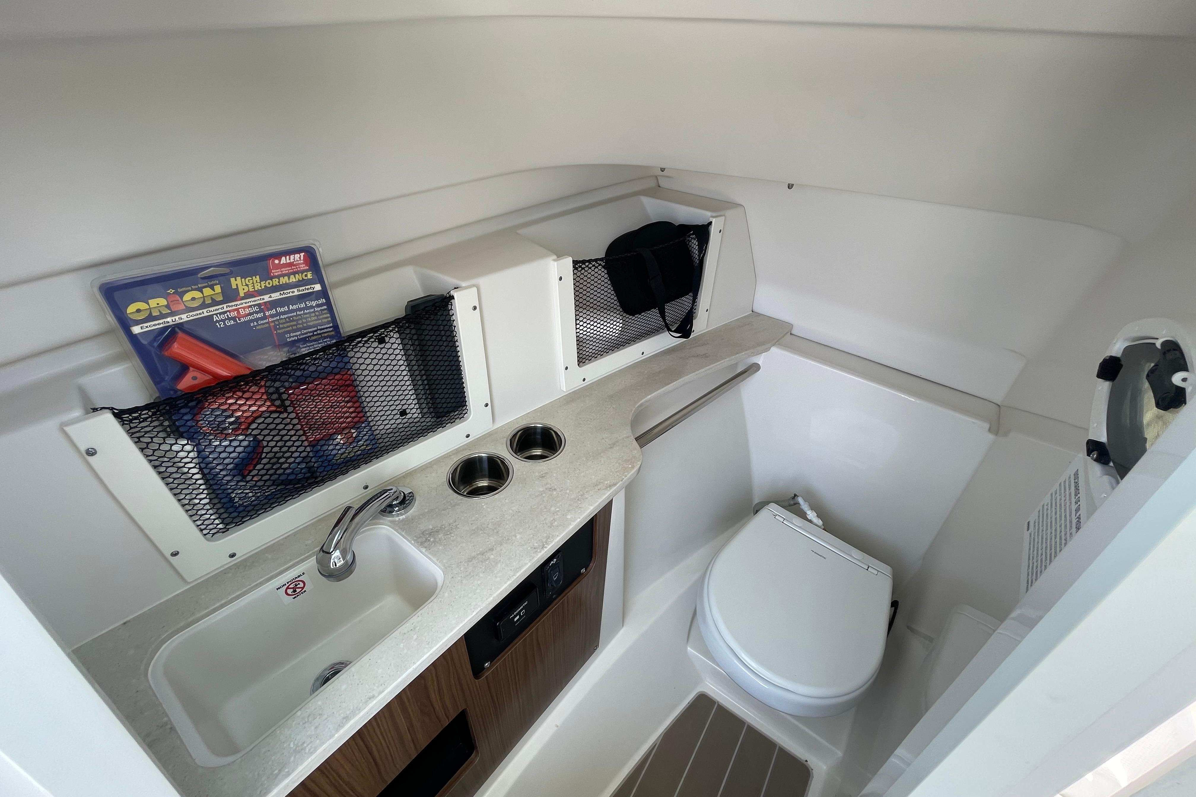 2022 Sailfish 245 DC boat interior with sink, toilet, and storage compartments.