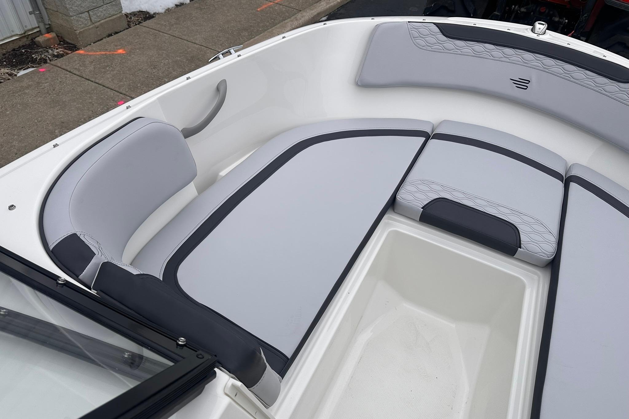 2026 Bayliner M17 boat interior with gray cushioned seating and storage compartment.