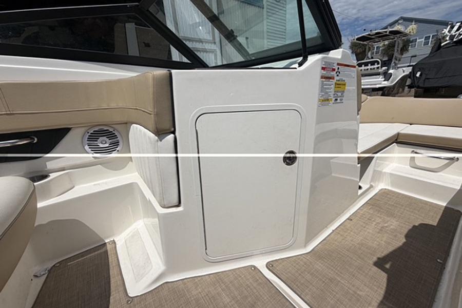Interior view of a 2018 Sea Ray SPX 190 boat, featuring beige seating and storage compartment.