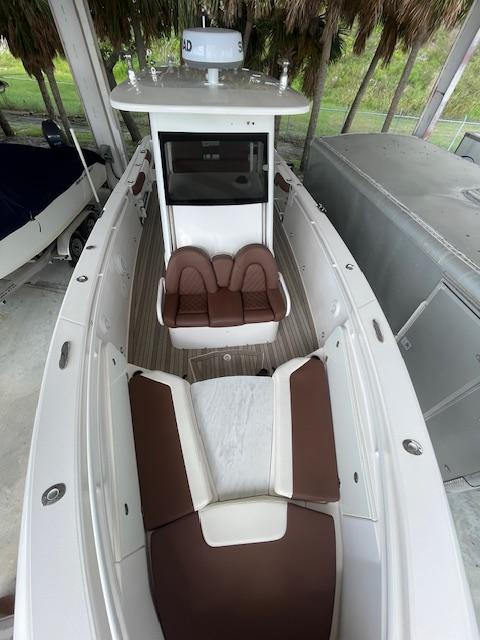 2014 Everglades 325 Center Console boat with brown and white seating, docked under shelter.
