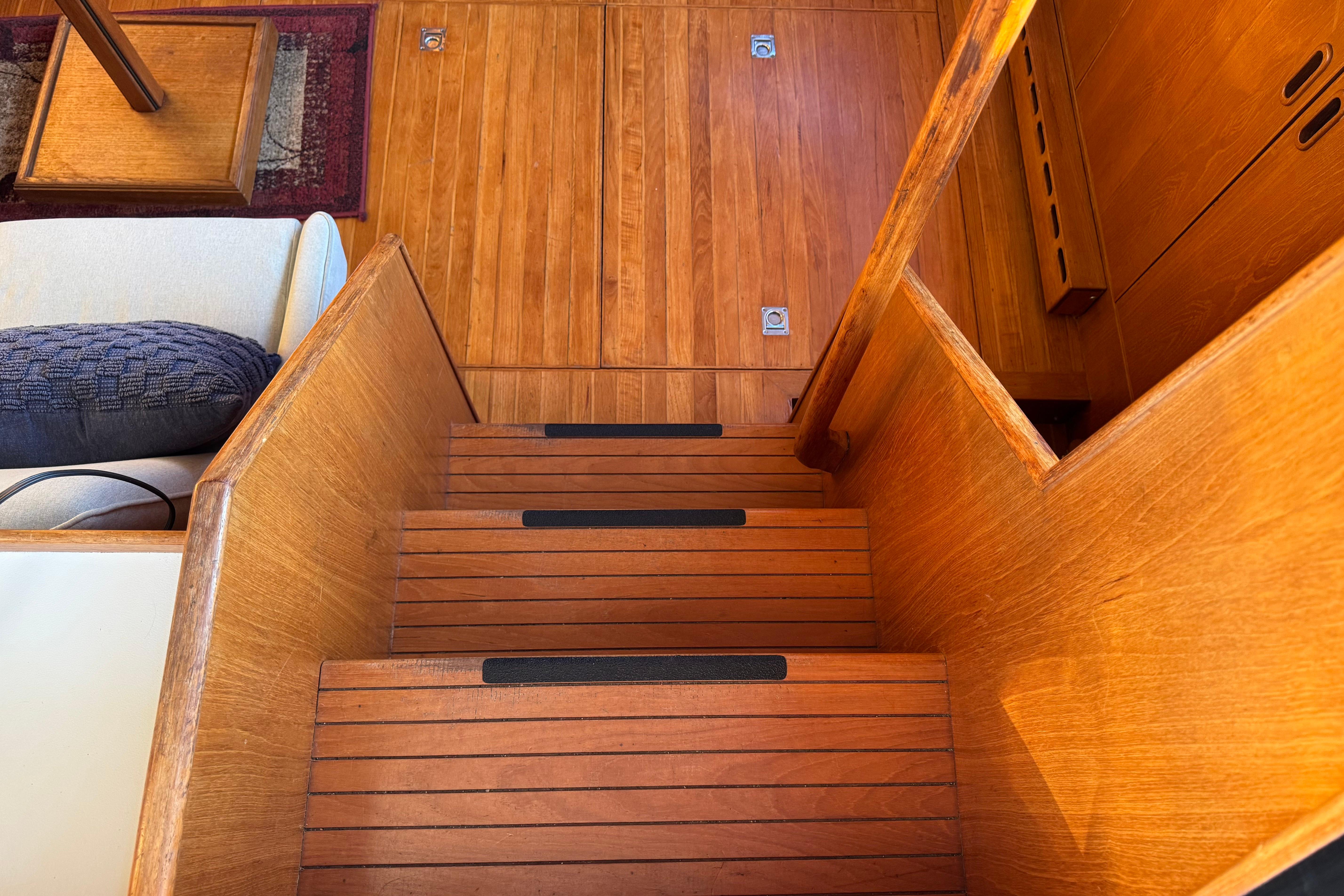 Wooden interior stairs on a 1987 President 37 yacht, featuring sleek design and warm tones.
