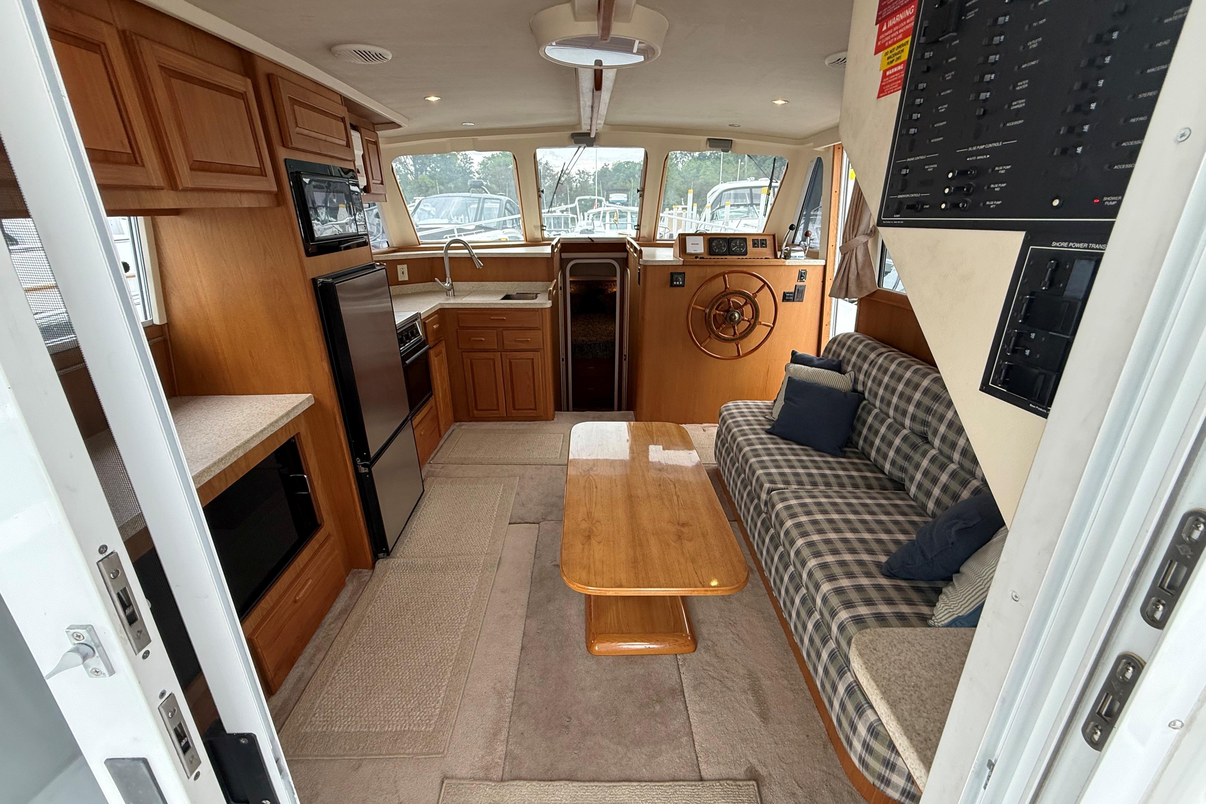 Interior of 1999 Mainship 350 Trawler with cozy seating, kitchenette, and helm station.