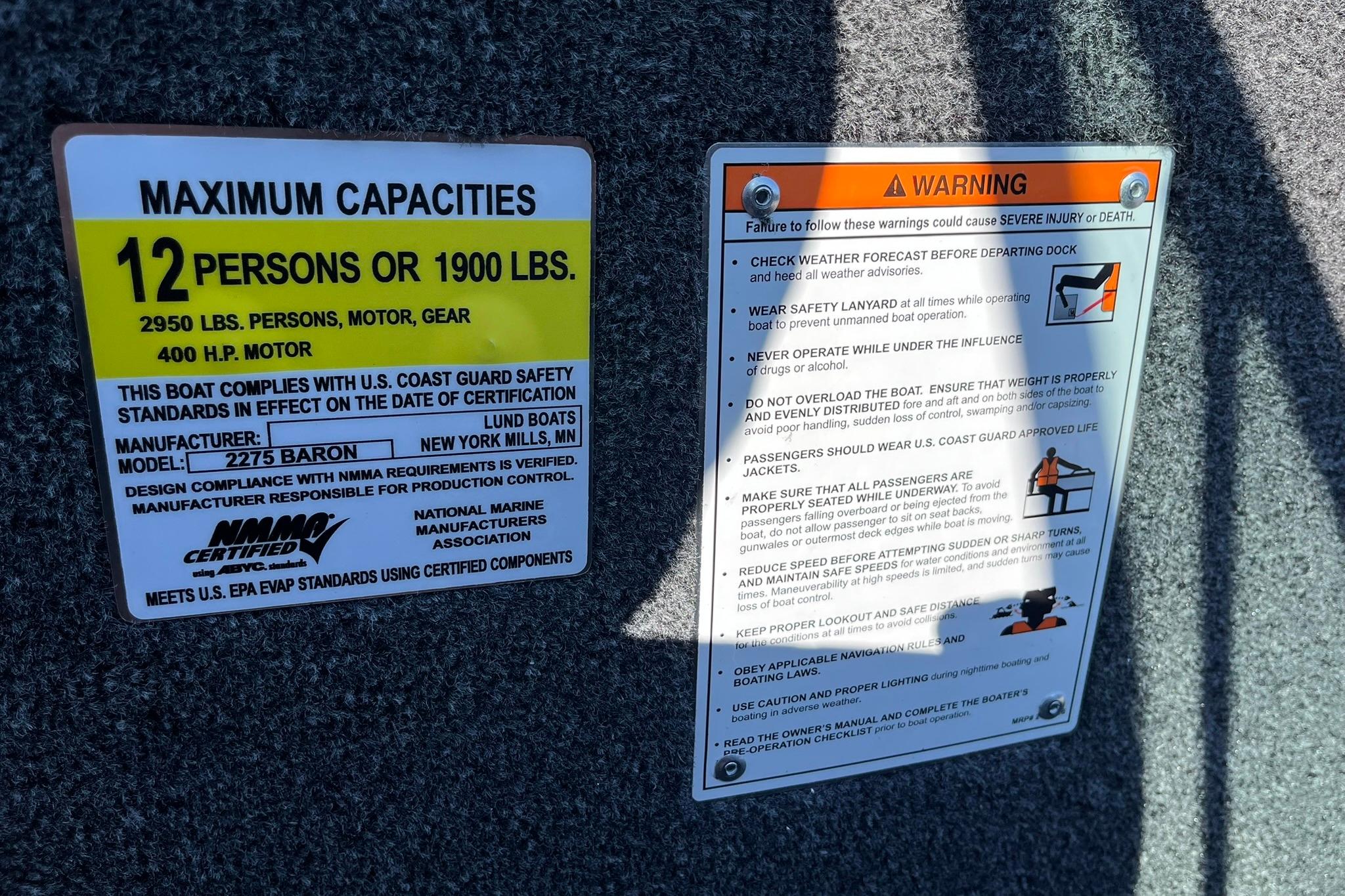 Safety and capacity labels on 2026 Lund 2275 Baron boat, 12-person limit, 400 HP motor.