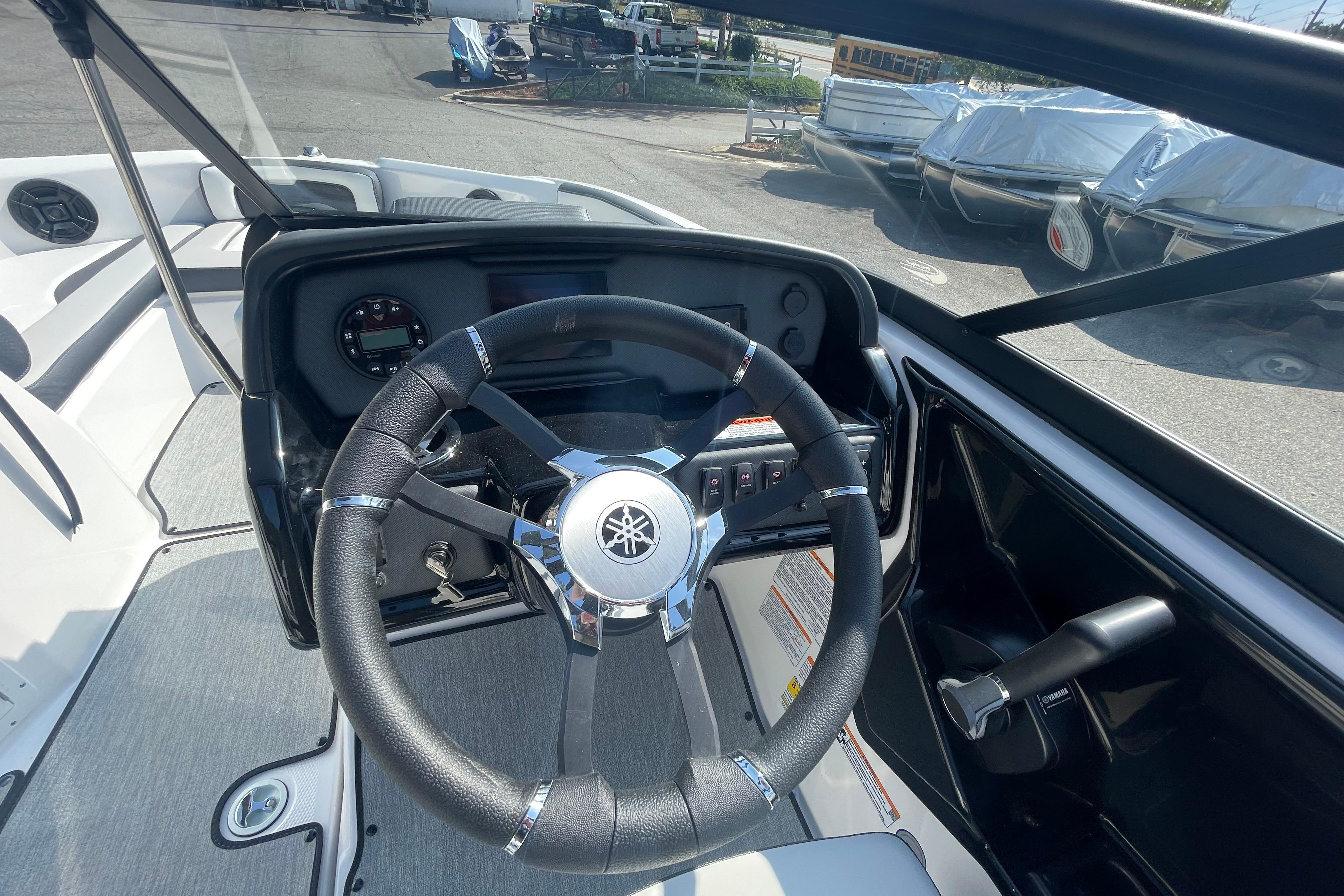 2026 Yamaha Boats AR195 steering wheel and dashboard in a marina setting.
