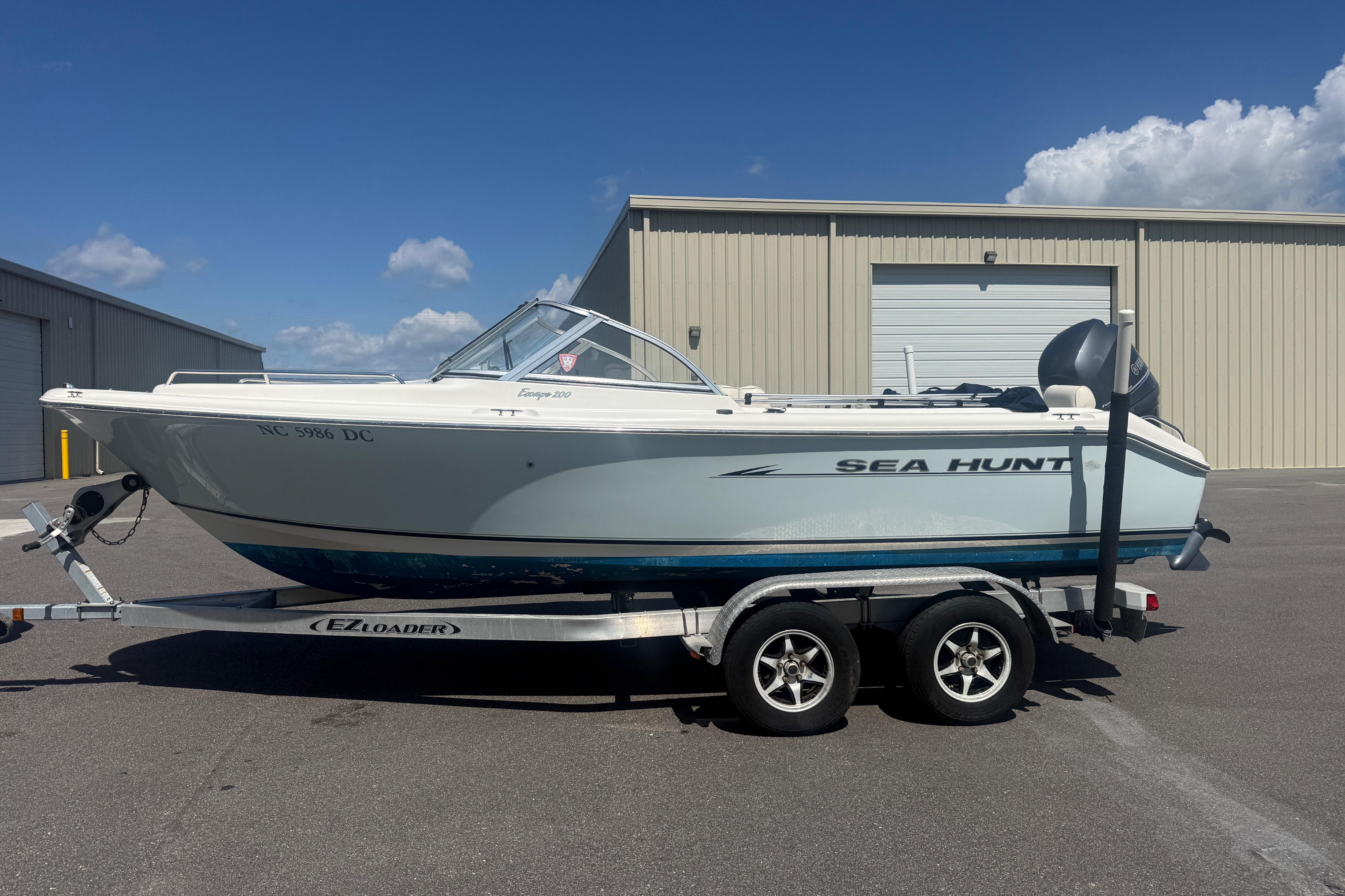 2006 Sea Hunt Escape 200 boat on trailer, parked outdoors under clear sky.