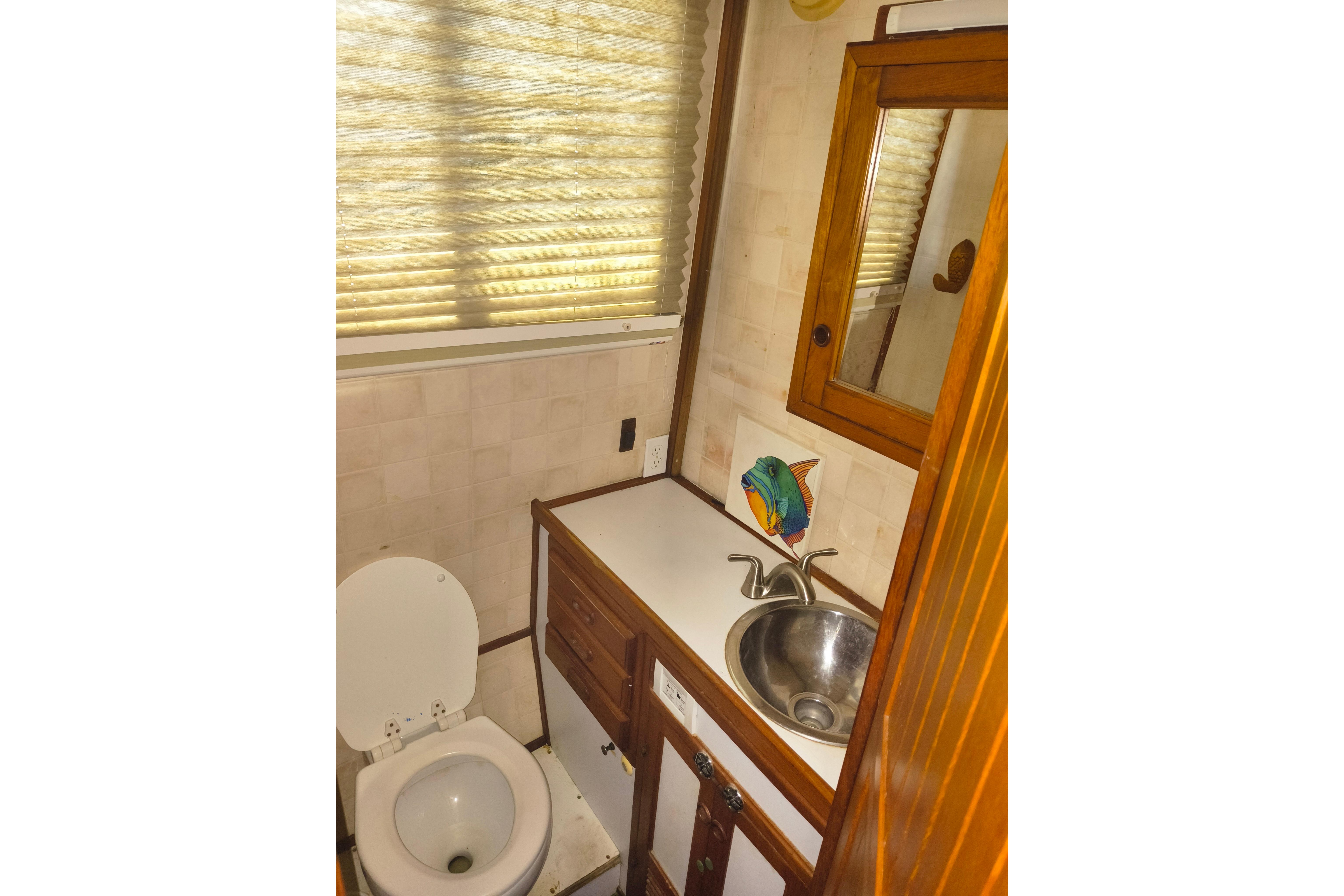 1984 Kadey-Krogen Manatee bathroom with sink, toilet, and fish decor.